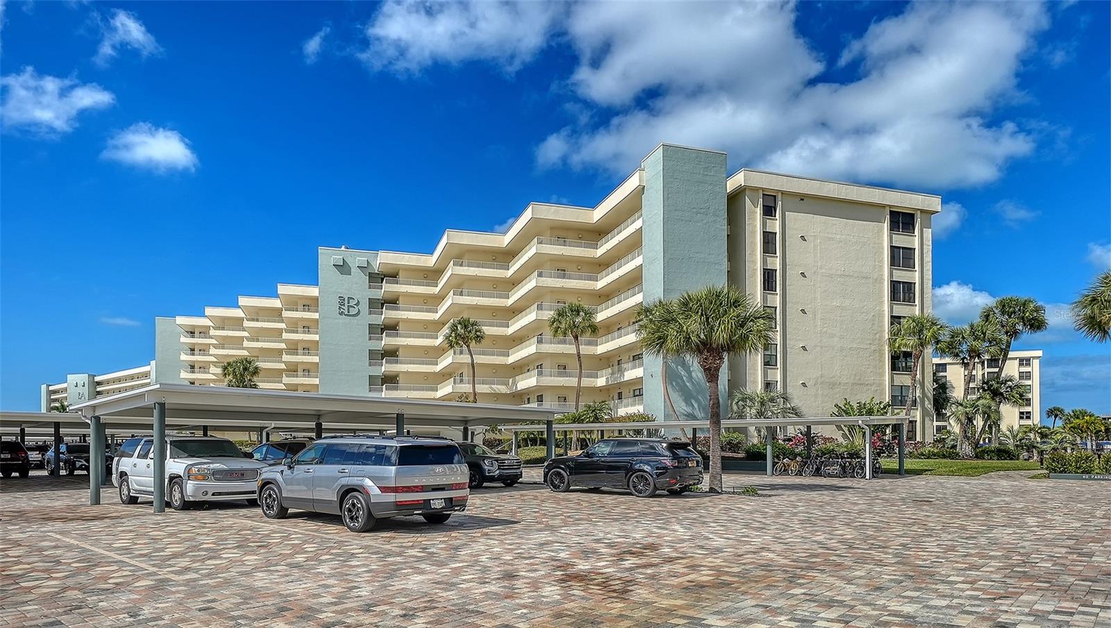Welcome to the effortless rhythm of island living at Gulf & Bay Club, one of Siesta Key’s most prestigious beachfront communities. Behind the 24-hour guard-gated entrance, this beautifully remodeled, rarely available, three-bedroom residence offers the perfect blend of comfort, privacy, and resort-style living in a setting that feels worlds away from the everyday.
Positioned on the first floor as a bright end unit, the home is surrounded by windows on three sides, filling the interior with natural light and creating a relaxed coastal atmosphere throughout. The thoughtfully redesigned floor plan opens beautifully for entertaining, with elegant finishes and carefully curated upgrades that make the residence feel both sophisticated and welcoming. The kitchen was designed with gathering in mind, featuring custom cabinetry, quartz countertops, marble backsplash, and premium Bosch appliances including induction cooktop and stainless vent hood. An additional built-in entertaining area with beverage refrigeration and extra storage makes hosting friends and family effortless. Living and dining areas flow naturally to the private lanai overlooking tropical landscaping and a tranquil lagoon, just steps to one of the community’s three pools, where evenings are often spent enjoying the peaceful surroundings and the soft glow of Siesta Key sunsets. The three-bedroom layout provides exceptional flexibility, whether for hosting guests, accommodating family, or creating a quiet home office. The primary suite offers a peaceful retreat with a walk-in closet and a beautifully updated bath featuring custom cabinetry, quartz countertops, and an expanded designer-tiled shower. Extensive renovations throughout the home include raised ceilings, smooth-finish walls, luxury flooring, updated lighting and electrical systems, new ductwork, upgraded panel box, air handler, and quick-recovery water heater. Importantly, the residence did not experience water intrusion during the recent hurricanes, offering additional peace of mind. Life at Gulf & Bay Club is defined by its resort-style amenities across 32 gated beachfront acres and 800 feet of Siesta Key’s famous quartz sand beach. Residents enjoy three heated pools including a lap pool, tennis and pickleball courts, racquetball, a large fitness center, beautifully landscaped walking paths surrounding the freshwater lagoon, clubhouses for gatherings, electric vehicle charging stations, and professional on-site management — all within a secure 24-hour guard-gated community. Just beyond the gates, the vibrant charm of Siesta Key Village awaits with its locally loved restaurants, boutiques, and island nightlife, while downtown Sarasota’s renowned arts and cultural scene is only a short drive away. This is more than a residence — it is an opportunity to experience the best of beachfront living on Siesta Key.