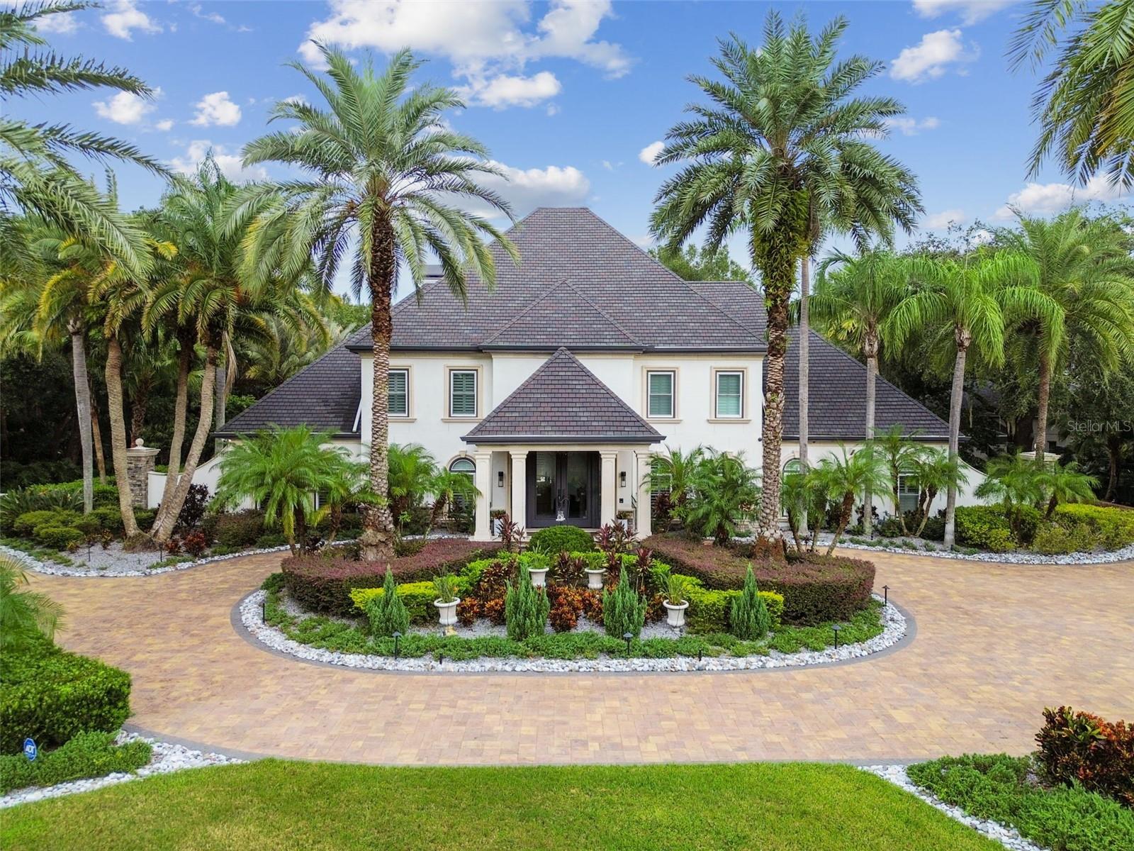 Situated in The Reserve at Tampa Palms, one of Tampa’s most prestigious gated golf course communities, this estate offers an extraordinary Florida luxury lifestyle. The community’s private club provides access to a fitness center, swimming pools, tennis courts, banquet facilities, and a fine-dining restaurant, creating the perfect blend of active living and social amenities. Fully updated in 2024, this luxurious home spans ¾ of an acre and presents a seamless combination of modern comfort and resort-style amenities.
This property’s outdoor oasis, honored with the Pinnacle Luxury Pool Award and The World’s Greatest Pool Award, was also featured on HGTV for its breathtaking design. The outdoor sanctuary includes a resort-style pool and spa, fountains, multiple fire pits, a striking fire sculpture, and a cozy fireplace. Entertain effortlessly with a fully equipped outdoor kitchen and bar, surrounded by 4 smartly placed TVs for game days or movie nights. The expansive backyard offers abundant space.
The huge circular driveway enhances the home’s curb appeal as you arrive under portico as guests are welcomed through an 18-foot custom front door. The grand entrance, with its 30-foot ceilings and curved staircase, offers a striking first impression. Inside, the home features elegant, open-concept spaces that make every moment feel special. The first-floor primary suite boasts a newly designed en-suite spa bath with a garden tub, multiple shower heads, water jets, and double vanities and a custom closet that will rival any other.
The heart of the home lies in the newly remodeled gourmet kitchen, featuring waterfall quartz countertops, top-of-the-line appliances, beverage drawers, a double oven, a pot-filler over the induction cooktop, and a dedicated drink and coffee bar. Whether hosting formal dinners in the stunning dining room, which includes a custom wine wall and built-ins, or enjoying casual evenings in the open living room with its coffered ceiling and fireplace, this home offers spaces designed for every mood and occasion.
Additional features include an executive office with custom cabinetry and display shelves, as well as a versatile third-floor bonus area. The entire top floor serves as an adult retreat, complete with a fitness area, media section, poker table, full bar, pool table, and half bath. Upstairs, there are 4 oversized bedrooms all with brand new en-suite baths.  The property has ample extra parking and 3 car garage, complete with a car lift—a dream setup for any car enthusiast.
With no detail left untouched, a resort style outdoor sanctuary, and multiple living areas, this estate embodies both luxury and practicality. The large backyard offers a perfect escape, while the seamless flow between indoor and outdoor spaces makes it ideal for entertaining.