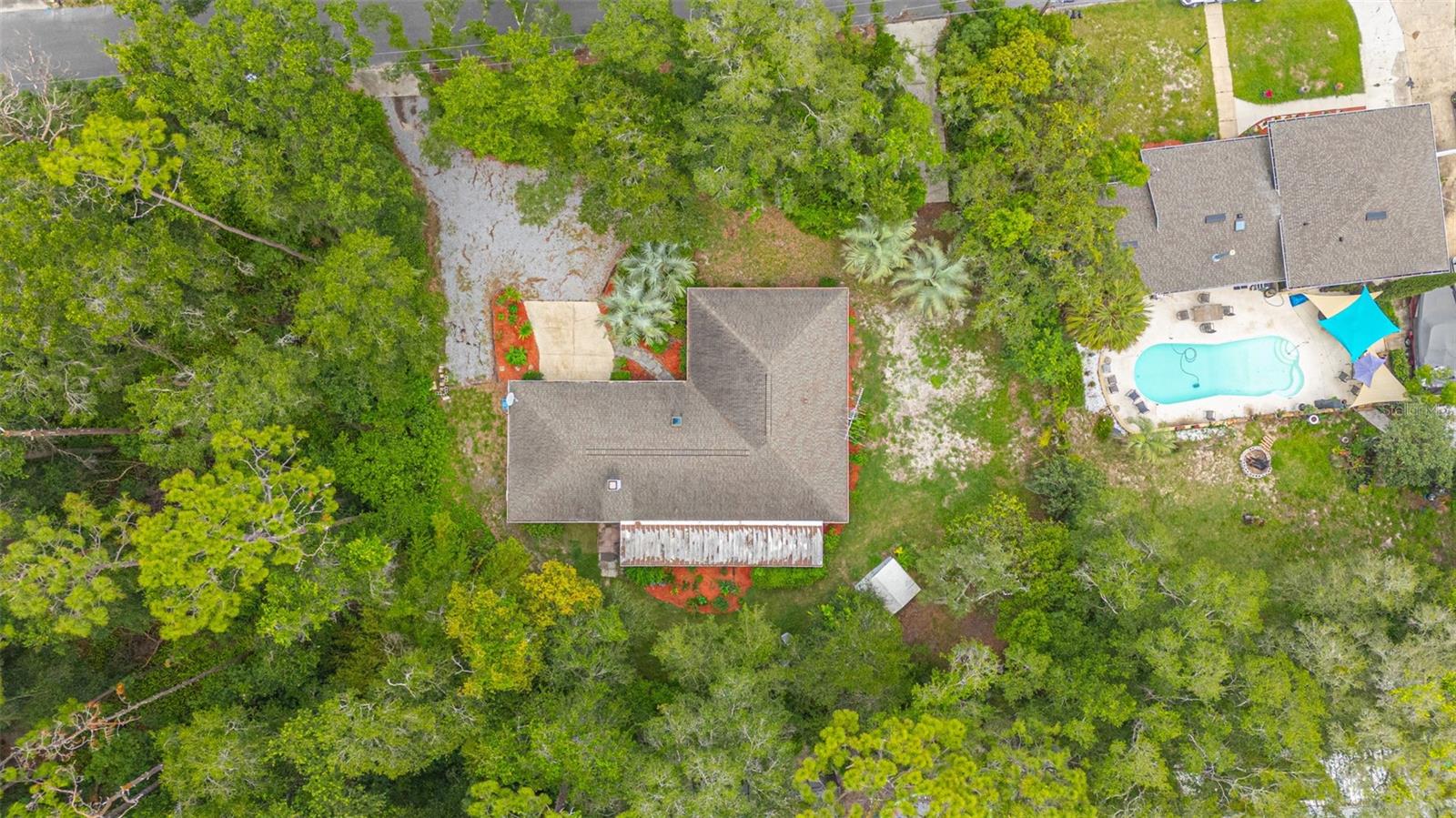 Welcome to a truly one-of-a-kind retreat in DeLand. Tucked away on a private .48-acre lot surrounded by mature landscaping, flowering plants, fruit trees, and herbs, this property offers a peaceful setting that feels worlds away while remaining conveniently close to everyday amenities. Inside, natural light fills the home's inviting living spaces. The heart of the home is the unique kitchen, dining, and bar area, where a cozy fireplace creates a warm gathering space unlike anything you've seen before. Multiple sets of French doors open to the expansive screened porch, seamlessly blending indoor and outdoor living and providing the perfect place to relax and enjoy the surrounding gardens. The flexible floor plan includes 3 bedrooms, 2 full bathrooms, an inside laundry room, and an impressive converted garage space complete with a private entrance, sink, storage, and closet space. Whether used as a home office, studio, hobby room, guest space, or creative retreat, the possibilities are endless. Outdoor enthusiasts will appreciate the gardener's paradise setting, complete with established landscaping, a storage shed, and two separate driveway entrances providing convenient access from Dartmouth Road. Additional features include a 2020 roof and a highly desirable location in one of DeLand's most charming neighborhoods, known for its rolling hills and mature trees. Conveniently located near Publix, Aldi, restaurants, shopping, and I-4, with Downtown DeLand just 10 minutes away. Enjoy an easy commute to Orlando or spend the day at New Smyrna Beach, both within convenient driving distance. If you've been searching for a home with personality, privacy, flexibility, and timeless charm, this exceptional property is ready to welcome you home.