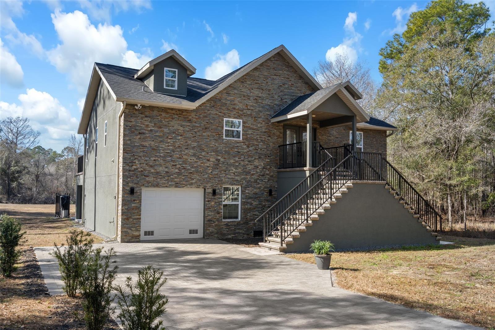 One or more photo(s) has been virtually staged. ENGINEERED AND BUILT FOR WATERFRONT LIVING! This stunning CUSTOM BUILT home offers direct WATERFRONT living on a serene canal that leads straight to the Withlacoochee River. Perfect for boating, fishing, kayaking, and enjoying Florida's natural beauty right from your backyard. Meticulously designed with PREMIUM FINISHES and thoughtful details throughout, this OPEN AND BRIGHT residence boasts SOARING VAULTED CEILINGS with beautiful SYNERGY TONGUE-AND-GROOVE PINE that create a warm, spacious feel. The primary living areas feature elegant crown molding, BEAM CEILINGS, recessed lighting, accent lighting, wall sconces, and a cozy electric fireplace with heater. NATURAL LIGHT floods the home through LARGE WINDOWS, 9' FRENCH DOORS opening to the balcony patio, and beautiful DOUBLE GLASS FRONT DOORS. The GOURMET KITCHEN is equipped with brand-new matching GE stainless steel appliances, including a WiFi-connected flat-top GE Smart range and air-fry oven, QUARTZ countertops, STONE backsplash, SHAKER STYLE SOFT CLOSE CABINETS. Counter-height vanities, FLOOR-TO-CEILING TILE, STONE ACCENTS AND QUARTZ countertops grace the stunning bathrooms. A Dual vanity Jack-and-Jill bathroom is located between the 2nd and 3rd bedrooms. Luxury vinyl plank (LVP) flooring is installed over extra underlayment for added comfort, complemented by 6" baseboards, solid core shaker-style doors throughout (including bedrooms, bathrooms, and laundry), and custom door and window casings. Additional highlights include a custom water filtering and water softener system, underground power to the home, gutters, blinds throughout, and a ship-lap wall accent in the primary bedroom. Step outside to discover exceptional outdoor living: a full brick paver driveway, extensive stone work (interior and exterior), stone walls, and brick accents. The 7.5 CAR GARAGE features a durable two-part epoxy-coated slab flooring. The 2nd-story deck/lanai features a custom paver finish, custom black aluminum railing, and stunning views overlooks the water, while the 400 sq ft dock provides direct access to your private canal and the Withlacoochee River beyond. Custom touches abound with low-voltage lighting along the driveway and stair entries, custom aluminum handrails throughout, and SOLID CORE INTERIOR DOORS. This one-of-a-kind, move-in-ready residence combines high-end craftsmanship, thoughtful design, and unbeatable waterfront location in a peaceful setting. Don't miss the opportunity to own this truly special custom-built canal-front home!