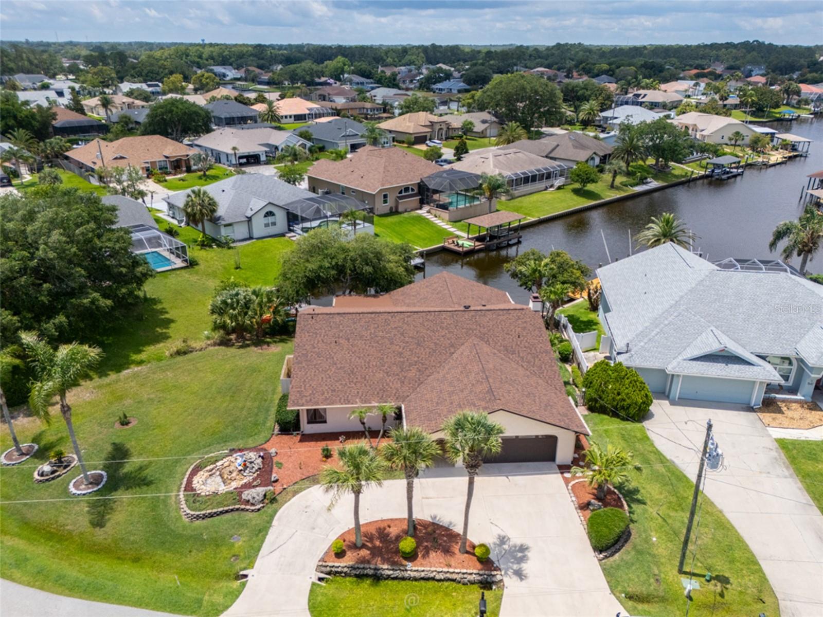 One or more photo(s) has been virtually staged. Welcomed by a circular drive and clean curb appeal, this SINGLE-story waterfront residence offers 2,169 square feet of beautifully modernized living space. Offering 75 feet of private saltwater canal frontage complete with its own dedicated dock, the property offers classic coastal leisure with fabulous upgrades, including a NEW roof (2024), a NEW HVAC system (2020), and NEW washer and dryer.
Inside, architectural scale takes center stage with soaring cathedral ceilings and an expansive floor plan designed for effortless hosting, with a formal dining room, formal living room  and family room with brick-accented wood-burning fireplace and a dedicated wet bar, all  anchored by the rich texture of newly sealed and polished travertine tile flooring. NO CARPET! 
The kitchen and both bathrooms have been fully remodeled, introducing clean lines, modern fixtures, and contemporary finishes.
Two sets of sliding glass doors bridge the interior with an impressive, 471-square-foot screened and tiled lanai. Equipped with cooling breeze fans, this expansive outdoor room acts as a front-row seat to the waterfront. Just beyond the screen, majestic, oak trees shade the water's edge. It is the ultimate setting to sit under the cool canopy of the grand oaks, watching spectacular evening sunsets reflect across the  canal. Situated on an oversized, 11,282-square-foot lot, the property leaves an impressive footprint with a  spacious side yard that allows more than enough clearing to design and build a custom pool. The front yard features a convenient circular driveway and an attached 2-car garage, providing generous parking and storage for gear and water toys. No HOA restrictions means total freedom to enjoy your property on your own terms. Located just minutes from local dining, boutique shopping, and less than 10 miles from pristine Atlantic beaches.