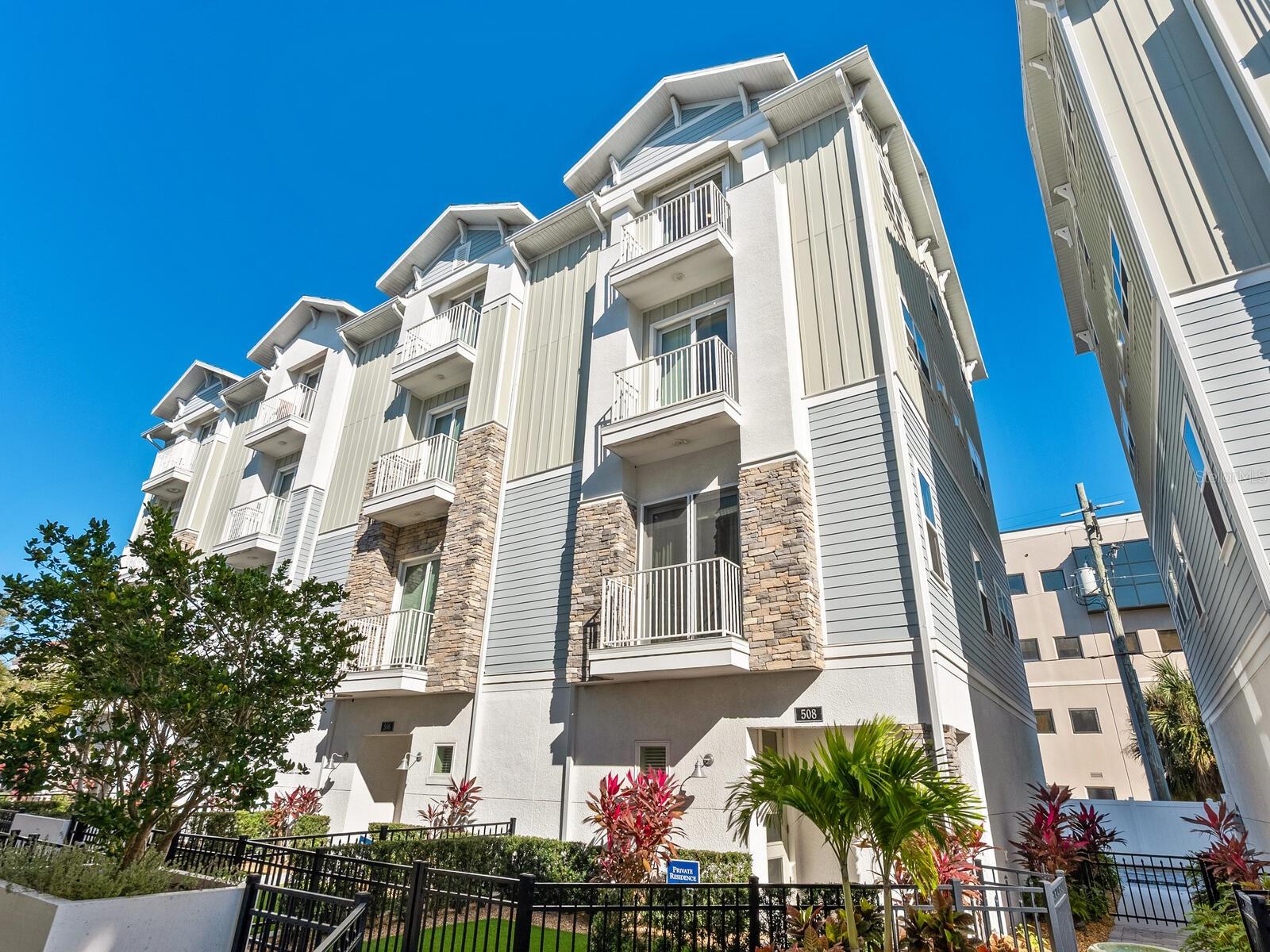It’s always about the experience of living downtown Sarasota from this four-story end unit townhome with elevator for convenience. Built to rigorous standards with impact windows and doors. Charming gated entry to home makes it inviting and to the foyer, where a private elevator provides access to every level of the home. First level with private two-car garage, oversized closet. Second level hosts the kitchen and open great room concept dining and living area. Also, an easily accessible powder room. Third level offers two spacious en-suite bedrooms with walk-in closets. Topping it all off, on the entire fourth level is a grand owner’s suite with walk-in closet, spa bath and thoughtful bar area with beverage refrigerator. Each floor/area of the residence has dual balconies for seamless indoor/outdoor living. The kitchen has on-point cabinet color with quartz counters, stainless appliances and induction cooktop with down-draft venting. Hardwood floors throughout the main living areas provide warmth and sophistication. This idyllic downtown location in the Enclave at Laurel Park is walking distance to the Bayfront Park, Ringling Bridge, Farmers Market, the Sarasota Opera, Van Wezel, fine dining, shopping and all that bustling Sarasota offers. Payne Park with tennis, playground, skate park are nearby as well as an extraordinary beach and boating lifestyle. Siesta Key and Lido Beach are moments away as is Legacy Trail and access to many parks and preserves. This extraordinary home is the ideal frame for an exceptional, easy living life!