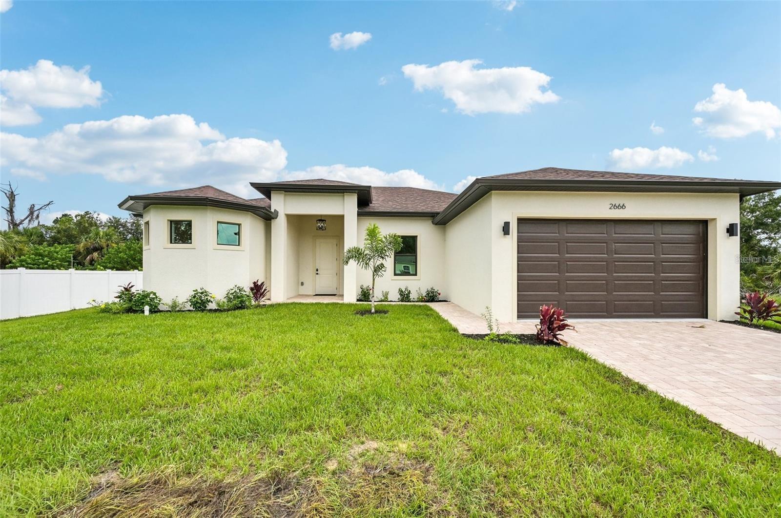 Virtually Staged. Oversized 12,592 SF lot! DCA Florida Homes is proud to present this exceptional property. The living space spans 2,079 square feet and includes a garage, entrance area, and an oversized lanai, bringing the total covered area to 2,880 square feet. With four bedrooms and two bathrooms, this home offers comfortable living for a family. Inside, you'll find high ceilings, with tray ceilings in the living room and master suite elevated to 11 feet, creating an open and spacious atmosphere. Large energy-efficient impact windows by ESW flood the interior with natural light, complemented by a massive 4-panel sliding glass door in the living room and an 8-foot French door leading from the master suite to the lanai. The kitchen is a chef's dream, featuring stainless steel Samsung appliances, upgraded cabinets with soft-closing hardware and crown molding, quartz countertops, full backsplash and an oversized island with a breakfast bar. The master suite is a true retreat, offering dual walk-in closets and a luxurious master bathroom with his and hers vanities, an oversized double walk-in shower with rain-head and handheld showers, and a freestanding soaking tub. The house is adorned with ceiling fans and chandeliers throughout, boasts a smart garage door opener, and features a driveway, footpath, and entrance areas paved with pavers. Additional highlights include shelving in closets, full front gutters, 8-foot front door and sliding glass doors, Carrera-style interior doors with contemporary square casings, and high-end luxury vinyl tile flooring throughout the house. This home offers a blend of modern luxury and comfort in a spacious and meticulously designed setting, enhanced by its oversized lot. Photos are of a nearly identical home by the same builder with the same floor plan and color scheme.