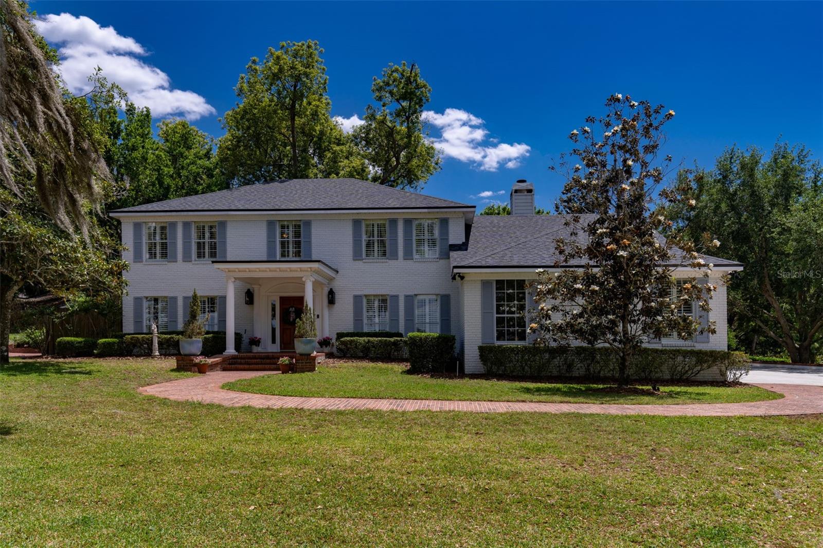 An incredible opportunity in one of Maitland’s exclusive communities offers stunning lakefront views of Lake Catherine and Lake Eulalia. With one of only three private docks on Lake Catherine, this is a rare and special property. A charming brick street winds along the lake and leads to this timeless residence, uniquely positioned with frontage on two lakes. This elegant two-story home features five bedrooms and sits on over an acre, providing exceptional privacy. Surrounded by indigenous Florida plants and abundant wildlife, the natural setting becomes part of your everyday lifestyle, making you feel like you are living in the countryside. A gorgeous solid wood Dutch door welcomes you into a gracious foyer with soaring ceilings and expansive windows that fill the home with natural light. Authentic oak floors extend throughout most of the home, complemented by custom detailed millwork throughout. Substantial crown molding in every room of the home draws the eye upward, adding depth and a polished, high-end finish to the interior. The layout includes a formal living, dining and great room along with a downstairs office or optional fifth bedroom for guests. A bright Florida room spans the back of the home and opens to outdoor living spaces and a new fire pit, perfect for entertaining. Custom built-ins and cabinetry, thoughtfully designed and crafted by Busby Cabinetry, enhance both beauty and functionality throughout this exceptional home. The kitchen opens seamlessly to the great room and features 42-inch cabinetry, a center island, high-end Thermador stainless steel appliances and exotic granite countertops. A breakfast room and additional peninsula provide ample space for casual dining and entertaining. The great room overlooks Lake Eulalia, while the living room and bedrooms capture serene views of Lake Catherine, both offering picturesque sunsets. Upstairs, the spacious primary suite includes an en-suite bath with dual sinks, a vanity area, a soaking tub and a walk-in shower. Additional bedrooms are generously sized and feature large closets. The light-filled Florida room connects to a bricked, covered porch with stately columns, creating an inviting indoor-outdoor flow. The backyard is framed by mature landscaping and shaded by a canopy of trees, offering a peaceful, secluded lakeside retreat. Recent improvements include a new roof (2023), new siding (2021), an updated dock, new garage doors and New Orleans-style lanterns. Additional upgrades include a new front Dutch door, spray foam energy-efficient insulation, walk-in closets in all bedrooms and an indoor laundry room. The three-car garage includes an EV charger, with one bay currently converted into a climate-controlled gym featuring rubber flooring and mirrors. The home is also equipped with two Rinnai tankless water heaters, wood plantation shutters, custom millwork, crown molding, wainscoting and chair rails throughout. Enjoy a short walk to downtown Maitland’s events, Lake Lily, the popular Sunday Farmer’s Market, the Enzian Theater and a variety of excellent restaurants. The brand new Maitland Library is being built around the corner. Watch Lake Lily fireworks from your private dock and benefit from easy access to I-4, Winter Park Village, and Park Avenue, all just minutes away.