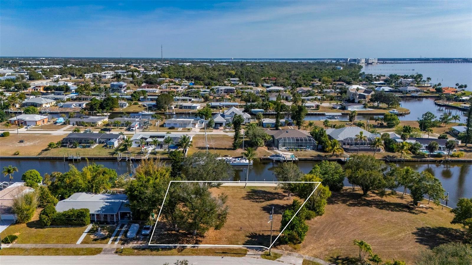 This exceptional .34-acre vacant waterfront lot offers direct sailboat access to the Gulf of Mexico with no bridges, and is ideally located just minutes by boat from the new Sunseeker Resort and downtown Punta Gorda. Directly across from Charlotte County’s Severin Park, the property enjoys a peaceful setting with attractive green space views. The lot measures approximately 95 feet across the front, 138 feet on the right side, 125 feet on the left, and offers 138 feet of waterfront. Extensive improvements have already been completed, including a new seawall cap, hydro-static pressure jet filters, and polyurethane-sealed seams installed by Florida Seawall Solutions in 2022. In 2023, a 97' x 8' marginal dock was constructed along the seawall, with all pilings wrapped in vinyl and cut 60 inches above deck height. The dock features Owens Corning “Barefoot Sands” composite decking, which stays cool even in high temperatures, along with two outer mooring poles. A fully loaded 16,000-lb Deco Concept CRS remote-operated boat lift was also installed, supported by four additional vinyl-wrapped lift pilings. Electric and water service run to the dock and include active 50-amp, 30-amp, and 110-volt outlets, as well as a waterline with backflow preventer. All sewer and water charges are current and paid monthly, allowing the future owner to avoid impact hookup fees when building. With its prime location, high-end improvements, and true sailboat access, this lot is an ideal site for your custom Gulf-access dream home.