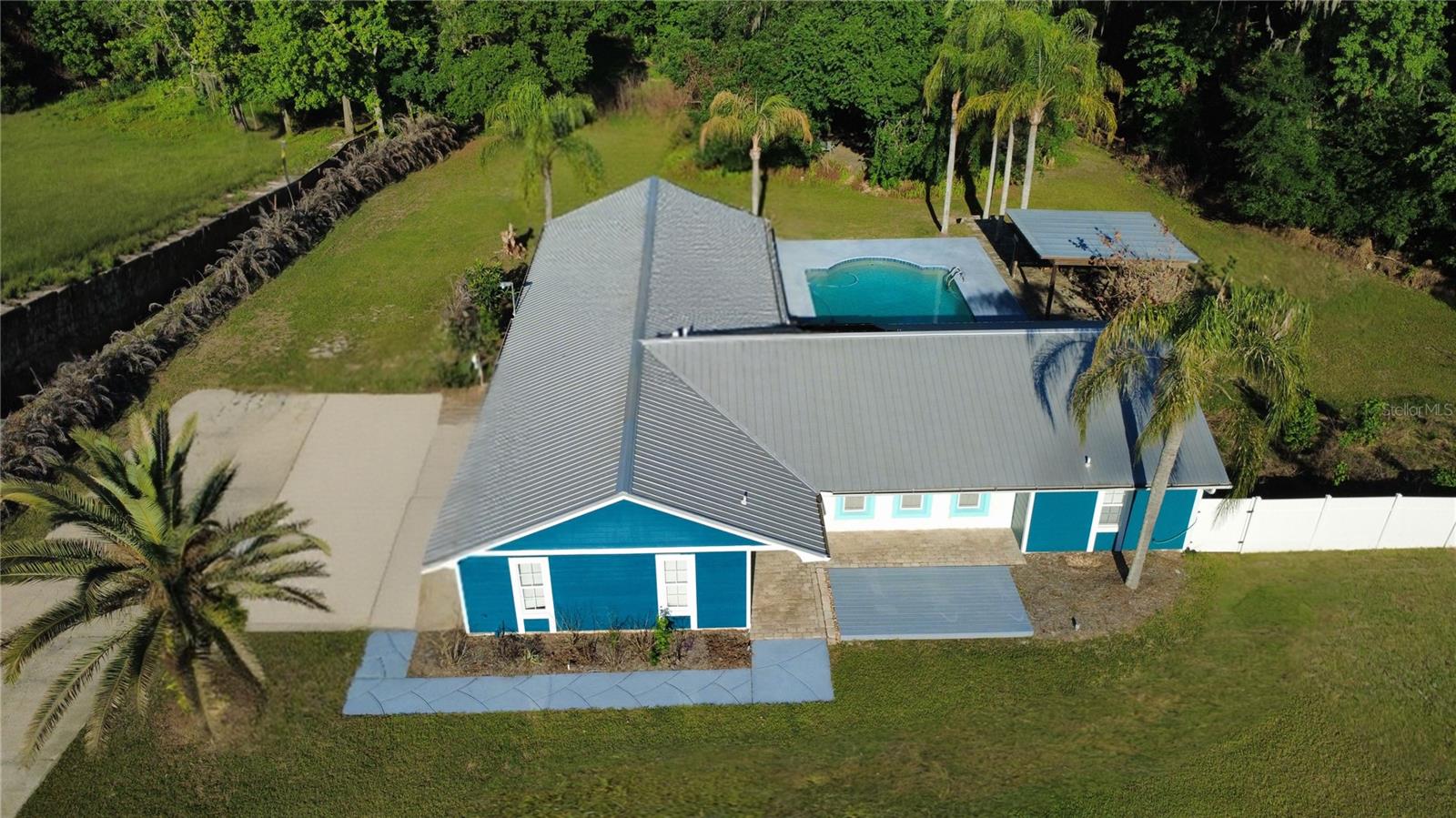 This beautifully updated 5-bedroom, 2-bath pool home in the highly desired Quiet Place community offers the perfect blend of country charm and modern convenience all with NO HOA and just minutes to everything. Filled with natural light, the home features a desirable split floor plan, fresh interior paint, a newer metal roof and A/C. The fully remodeled kitchen is open and inviting, showcasing granite countertops, custom cabinetry, crown molding, stainless steel appliances including a wine cooler, a breakfast bar, and a picturesque view of the pool. The spacious primary suite offers private pool access, a large walk-in closet with built-ins, and a fully renovated bath with dual granite vanity and tiled walk-in shower. Living and dining areas feature soaring ceilings, a cozy wood-burning fireplace, and seamless access to the outdoor pool area, which includes an outdoor shower. Step outside to your private backyard oasis complete with a palm-lined, solar-heated pool, a stone-accented covered veranda, and added privacy with no visibility from neighbors.  Additional highlights include new luxury vinyl plank flooring, a variable-speed pool pump, updated lighting, dual-pane windows, Culligan water softener, security system with cameras, and ample parking. The oversized 2-car garage offers extensive storage and workspace on the 2.4 acre homestead, which is planted with banana, mulberry, and avocado trees.