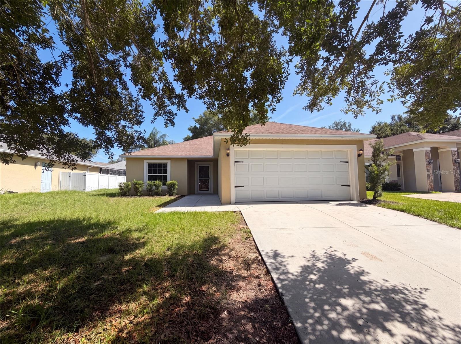 Virtually Staged. 33137 Irongate Dr is a one-story Leesburg home built in 2018 with an open-concept layout. The kitchen has granite countertops, stainless steel appliances, and white cabinetry with a breakfast bar for casual seating and added prep space. The main living area features vaulted ceilings and a sliding glass door that connects to the backyard, extending usable space outdoors. The primary bedroom includes a walk-in closet for organized storage and an en-suite bathroom with a walk-in shower. Additional bedrooms and full bathrooms with tub-and-shower combinations provide comfortable accommodations, while a concrete patio and open backyard add room for outdoor use. A two-car garage completes this well-maintained residence with practical amenities throughout.. Included 100-Day Home Warranty with buyer activation