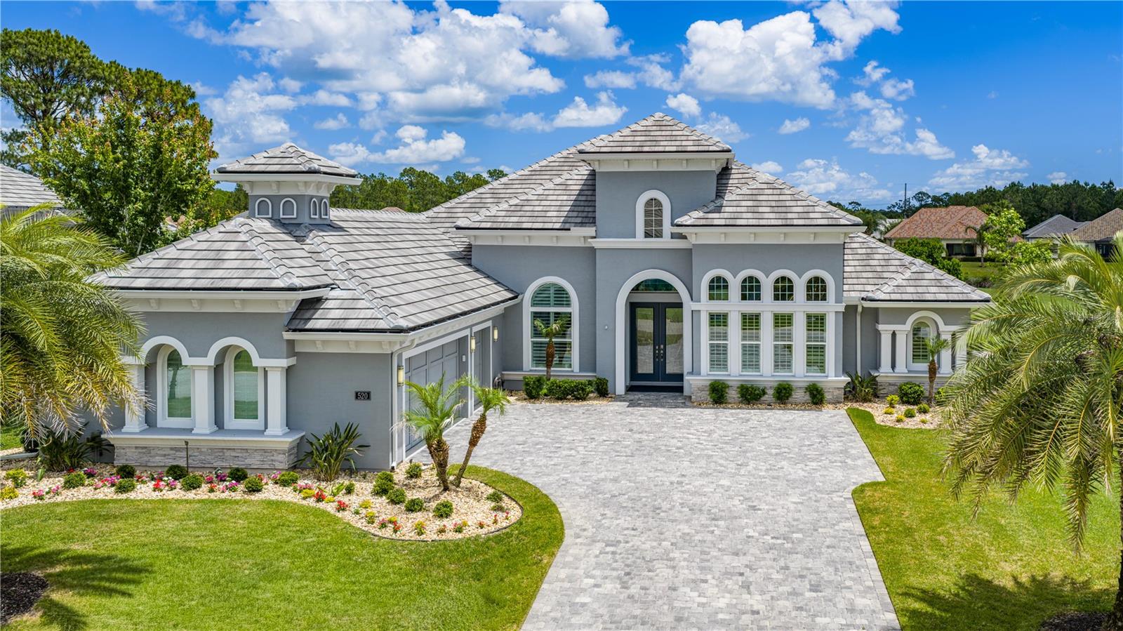 One or more photo(s) has been virtually staged. Step into luxury with this stunning estate home located in the prestigious gated community of Plantation Bay Golf & Country Club. Perfectly positioned on the Westlake golf course, this custom residence offers exceptional curb appeal with a flat tile roof. A grand double glass door entry welcomes you into the impressive foyer, where soaring ceilings, elegant finishes, and golf course views stand out.The spacious family room features tile flooring, 12-foot ceilings with a 13-foot tray ceiling, custom built-in cabinetry beneath the TV, and four 10-foot vanishing sliders with electric blinds that open to the outdoor living space. The formal dining room is designed for entertaining with tile floors, a large picture window, double crown molding, and a tray ceiling.The gourmet kitchen is beautifully appointed with Cambria quartz countertops, a large center island with storage, Kohler sink, tile backsplash, two-tone cabinetry, built-in oven, GE Profile stainless steel appliances, Samsung refrigerator, and two pantries including a walk-in closet pantry and additional built-in cabinetry. The breakfast nook is surrounded by windows overlooking the golf course and offers direct access to the lanai.The luxurious primary suite features golf course views, plantation shutters, crown molding with tray ceiling detail, plush carpet, two custom walk-in closets with built-ins, and private lanai access. The spa-like primary bath includes an oversized tiled walk-in shower, extended quartz dual vanity, and separate commode room.Bedroom 2 offers plantation shutters, wood shelving, carpet flooring, and access to the Jack-and-Jill bath complete with quartz countertops and tiled tub/shower combination. Bedroom 3 features tile flooring, plantation shutters, two closets with custom built-ins, and a private en-suite bath with quartz countertops, tiled walk-in shower, and direct lanai access. Bedroom 4 is ideal as an office with tile floors, large windows, plantation shutters, and built-in closet.Outdoor living is exceptional with an extended covered paver lanai showcasing golf course views, frameless screen enclosure, and no-see-um screens. The outdoor kitchen is equipped with propane grill, sink, and refrigerator, while outdoor electric hurricane screens enhance comfort year-round.Additional upgrades include WHOLE HOUSE GENERATOR, whole house water filtration system, plantation shutters throughout, oversized laundry room with cabinetry, utility sink, extended counter space, surround sound interior/exterior, security system, 2 zoned HVAC system, Cambria quartz throughout, and touchless kitchen faucet. Exterior stone accents, lush landscaping with lighting, rock beds, gutters, private mailbox, and an oversized paver driveway lead to the side-entry 3-car garage with custom cabinets. Electronic hurricane screens on both the front entry and rear lanai provide added convenience and peace of mind.Located in Plantation Bay Golf & Country Club, residents enjoy optional memberships with 45 holes of championship golf, Founders Clubhouse, fitness center, resort-style pools, tennis, pickleball, bocce, cabana bar, and an active social calendar all conveniently close to beaches, shopping, dining, and I-95. Buyers receive a substantial discount on initiation fee, ask listing agent for details.This exceptional estate home is more than a residence it’s a lifestyle, offering luxury upgrades, golf course views, and beautifully designed indoor and outdoor living spaces.