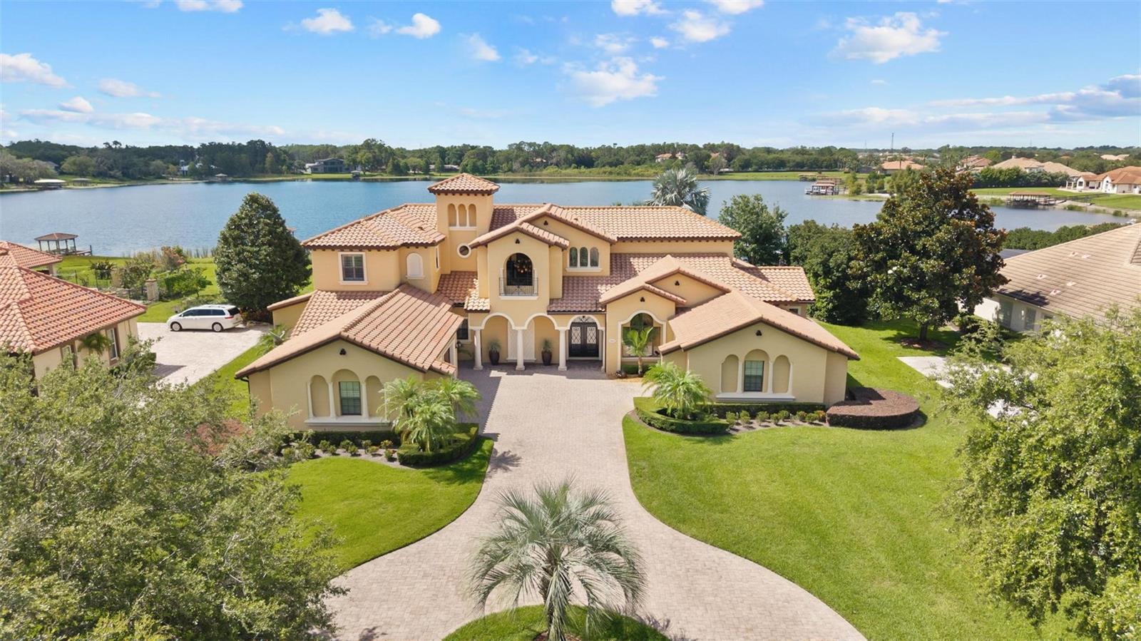 Under contract-accepting backup offers. Experience Unmatched Lakeside Luxury in a Custom-Built Masterpiece
Discover the pinnacle of elegance and tranquility in this exquisite custom-built estate, ideally positioned on an expansive lot within an exclusive guard-gated community. With direct access to a crystal-clear spring-fed lake that permits private boat docks, this home offers a rare blend of relaxation, recreation, and refined living.
Step inside to a beautifully designed open-concept living space where the family room and gourmet kitchen seamlessly connect. The kitchen is a chef’s dream, featuring top-of-the-line appliances, a breakfast bar, an inviting eat-in nook, and a spacious butler’s pantry. A custom wine closet nearby provides a perfect display for your finest vintages.
Adjacent to the kitchen, a well-appointed guest suite and a large laundry room enhance the home's convenience. The formal dining and living rooms, centered around a cozy shared fireplace, has stunning views of the lake—creating a warm and relaxed setting for entertaining.
The first floor also features a private office, a full pool bathroom, and a luxurious primary suite. This expansive retreat includes a dedicated exercise room, while the spa-inspired en-suite bath boasts double vanities, dual walk-in closets, a garden tub, and a walk-through shower.
A beautifully crafted wood and iron staircase leads to the second floor, where you'll find two spacious bedrooms, each with its own private bathroom. The expansive game room opens to a lake-view balcony, perfect for taking in serene sunsets. Movie nights are elevated in the state-of-the-art home theater, complemented by a convenient half bath.
Step outside to your own private paradise—an entertainer’s dream. The large covered lanai includes a fireplace and a fully equipped summer kitchen. A sparkling pool and spa, along with a generous open patio, set the stage for unforgettable gatherings or peaceful evenings under the stars—complete with views of the nightly fireworks.
Rounding out this extraordinary residence is a three-car garage, offering ample room for vehicles and recreational equipment.
This is more than a home—it’s a lifestyle. Luxury, privacy, and breathtaking views await. Schedule your private tour today and experience the ultimate in lakeside living.