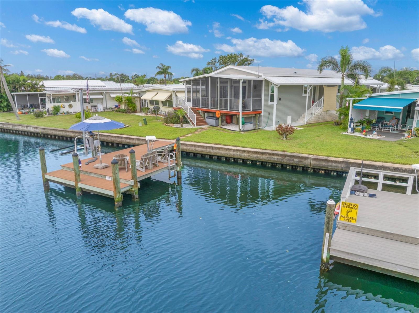 BEAUTIFUL WATERFRONT home nestled on a saltwater canal, built in 2019, and 9 feet above sea level, this home has 2-bedroom, 2-bath and den, and offers the perfect blend of comfort, style, and coastal living.  (Interior photos to follow) With approximately 1500 sq ft of living space, this spacious home features an open and inviting layout enhanced by crown molding throughout, luxury vinyl plank flooring in living areas and kitchen, and elegant plantation shutters that remain with the home.  The gourmet kitchen has quartz counter tops, stainless steel appliances, abundant wood cabinetry, a gas stove, and plenty of workspace for cooking and entertaining.  You'll appreciate the generous storage throughout, including oversized closets and numerous cupboards.  The convenient indoor laundry room includes a utility sink and more cupboards for added functionality. washer & dryer do not convey. Recent updates and amenities include A/C (2024), roof-over (2024), tankless water heater, water treatment system, reverse osmosis, and gas hookup capacity for outdoor grilling.  Double sliding doors open to an expansive 160 sq ft screened lanai built on piers, providing a perfect place to relax and enjoy the peaceful waterfront views of the mangroves.  Beneath the lanai is open storage space for all your outdoor gear.  Outside, the composite dock provides easy access to boating, fishing, and kayaking, with small boat lift for boat or jet ski.  The double-door shed with loft offers ample room for storage and large enough for your golf cart.  An additional parking pad with optional shade sail is an ideal space for auto or golf cart parking, and the carport allows side by side parking for 2 vehicles.  Enjoy this active 55+ community with many activities and clubs.  Price includes share for the lot and ownership in the community.  The $410 HOA includes water, sewer, trash pickup, lawn mowing/edging, heated pool, fitness room, billiards, clubhouse, shuffle, bocce, 2 boat launches,  fishing pier, and access to Tampa Bay with no bridges.  Community is 10 minutes to downtown St Petersburg, 15 minutes to 2 airports and 20 minutes from the beaches.  This is one that you will want to check out!