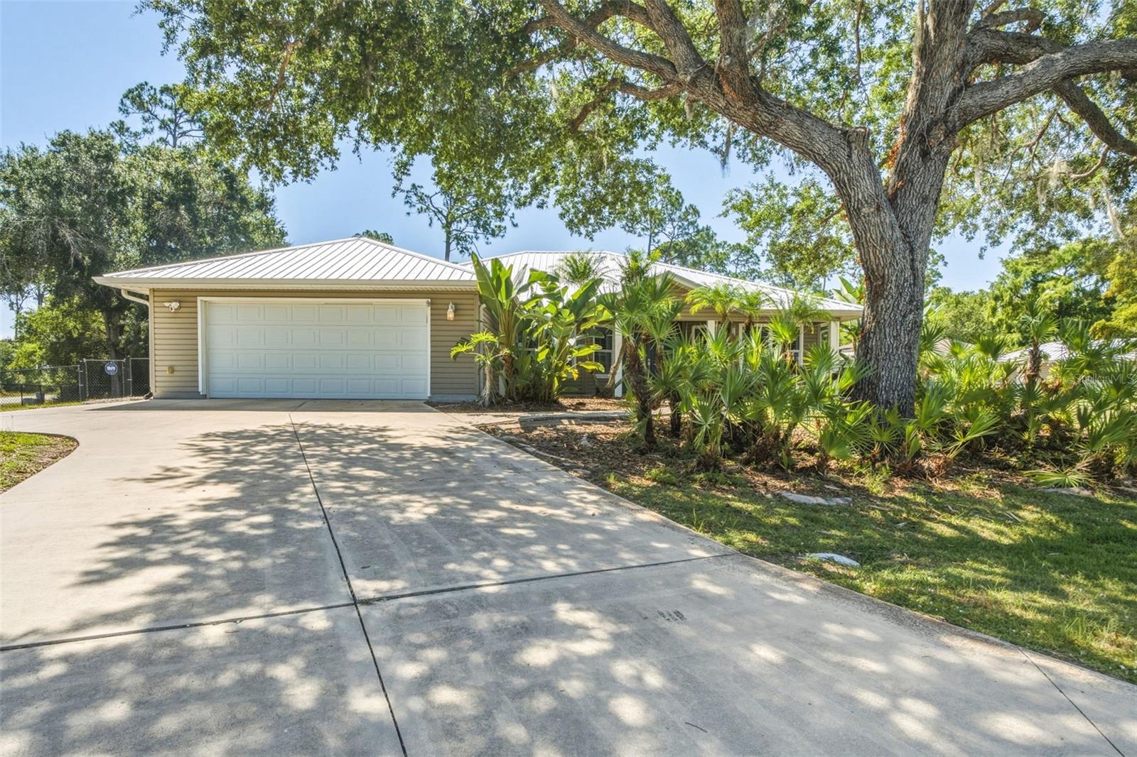 A RARE ESTATE-STYLE OFFERING: TWO RESIDENCES, SALTWATER POOL, SEPARATE BOAT HOUSE/CARPORT, AND OVER HALF AN ACRE OF REFINED FLORIDA LIVING. 

Discover an exceptional multi-residence retreat set on an oversized corner double lot just over ½ acre. This private compound blends architectural character, modern updates, and resort-style outdoor living, offering a rare level of versatility and sophistication.

PRIMARY RESIDENCE – 1,754 SQ.FT., 3 BEDROOMS + OFFICE, AND 2 BATHS:  
The main home exudes luxury with high cathedral ceilings, recessed lighting, and striking industrial-style multi-blade fans that define the open living space. Smooth arched pass-throughs, plantation shutters, substantial baseboards, and crisp white crown molding create a refined, cohesive aesthetic throughout.

Modern luxury vinyl plank flooring in multi-toned gray anchors the main living areas, complemented by wood-look laminate in all bedrooms. Dual multi-pane French doors open to an expansive brick-paved pool terrace, enhancing the home’s seamless indoor-outdoor flow.

The kitchen is a designer focal point, featuring a solar tube skylight, stainless steel appliances, raised-panel oak-style cabinetry, rich granite surfaces, and custom blue-grey accent canopies supported by cylindrical columns with integrated lighting. The raised bar offers an elegant space for casual dining and entertaining.

The ensuite primary bedroom is a private sanctuary with a glass-block shower wall, solar tube skylight, and a custom built-in closet system. French doors provide direct access to the pool deck for a true resort-style experience.

Exterior highlights include a circular driveway, large covered front porch with decorative double-door entry, mature oaks and native palms, hurricane shutters, a 2023 metal roof, and a transfer switch for portable generator use.

OUTDOOR LIVING: The free-form saltwater pool with sun shelf is framed by an expansive brick-paved terrace, offering the perfect setting for relaxation and entertaining. A walkway leads to the boat house with carport/storage and the detached guest residence.

GUEST RESIDENCE – BUILT 2013, 484 SQ.FT., 1 BEDROOM, 1 BATH:
The separate guest home provides luxurious privacy with its own entry porch, living room, full kitchen, and ensuite bedroom/bathroom—ideal for extended family, guests, or premium rental income.

A LUXURY COMPOUND WITH ENDLESS POSSIBILITIES.   
This exceptional property offers space, privacy, and multi-residence flexibility rarely found in the area—perfect for those seeking an elevated Florida lifestyle on a beautifully oversized lot.