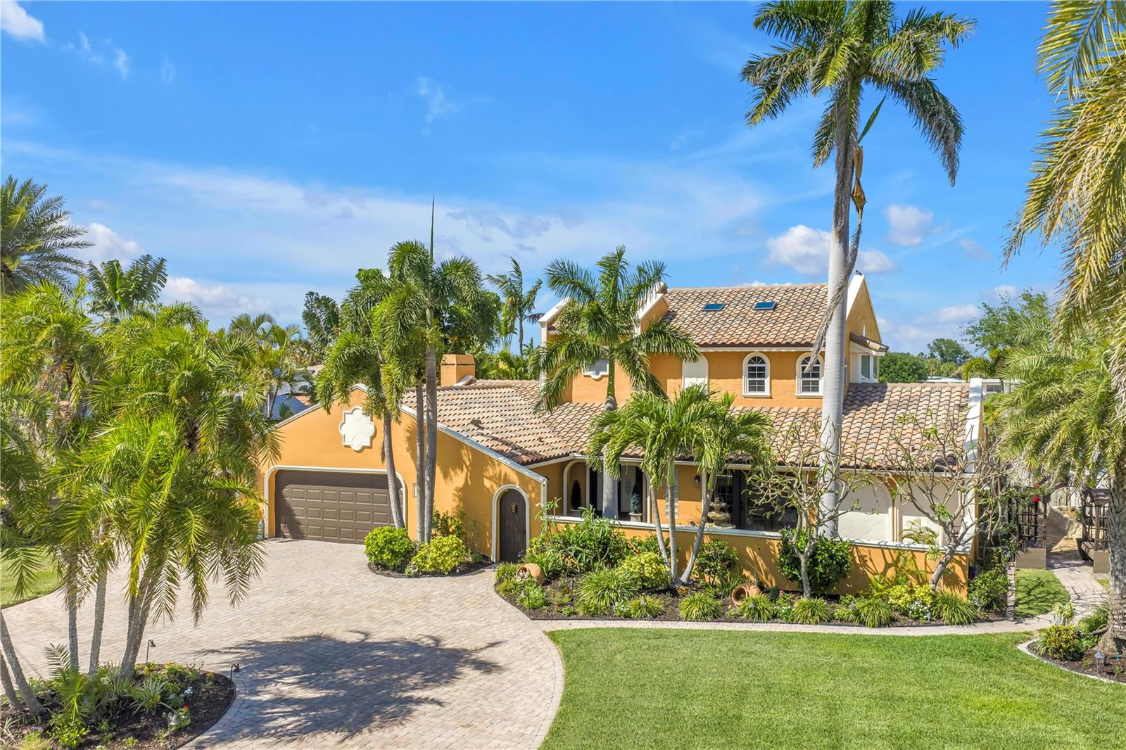 There are waterfront homes... and then there are homes that transport you somewhere else entirely.
Hidden behind swaying royal palms and lush tropical gardens, on a large corner lot, this extraordinary Spanish Mediterranean waterfront estate evokes the romance of an Italian villa while embracing the beauty of St. Pete Beach living. From the moment you arrive, the circular drive, tranquil courtyard fountain, handcrafted architectural details, and mature botanical gardens create an atmosphere that feels worlds away from everyday life.
Steeped in local lore, this Belle Vista estate is said to have once hosted elegant gatherings under the ownership of a British noble. Whether legend or fact, the home still feels perfectly designed for unforgettable evenings with family and friends.
Architectural artistry unfolds throughout with graceful archways, decorative friezes, soaring ceilings, textured walls, artisan niches, distinctive quatrefoil windows, and a dramatic curved wrought-iron staircase that creates an unforgettable first impression. Rich craftsmanship and timeless character define every space.
Designed for both everyday living and grand entertaining, the residence offers five bedrooms, including dual primary suites—one on each level—providing exceptional flexibility for guests or multi-generational living. The formal living room is anchored by a magnificent carved stone fireplace, while walls of glass frame sparkling water views throughout the home.
At the heart of the residence, the chef's kitchen combines elegance and function with a Monogram professional refrigerator, GE Café six-burner gas range, convection oven, warming drawer, Bosch dishwasher, custom cabinetry, Brazilian granite countertops, integrated wine refrigeration, and a stunning brick-lined wine grotto that serves as both art and conversation piece.
Just beyond, the custom waterfront bar and piano room invite evenings filled with music, conversation, and breathtaking sunsets over Boca Ciega Bay.
Upstairs, the luxurious primary suite offers a private waterfront balcony, spa-inspired bath with a freestanding soaking tub, custom multi-head shower, and designer finishes that create a true owner's retreat.
Outside, winding garden paths, colorful flowering landscapes, peaceful courtyards, and professionally designed landscape lighting transform the property into a private Mediterranean-inspired sanctuary. The resort-style pool with waterfall spa, expansive entertaining decks, and elevated observation terrace create the perfect setting for both intimate gatherings and large celebrations.  
Boaters will appreciate deep-water access, a private dock with a 12,000-pound lift, and quick access to the Intracoastal Waterway and the Gulf of Mexico.
Thoughtfully updated throughout, the home features an Eagle tile roof, smart home technology, propane system, updated water heaters, enhanced pool systems, integrated landscape lighting, and numerous designer upgrades that preserve its timeless architectural integrity while providing modern comforts.
Ideally located just moments from award-winning Gulf beaches, renowned dining, shopping, golf, downtown St. Petersburg, and Tampa International Airport, this remarkable residence offers a rare opportunity to own not simply a waterfront home, but a Mediterranean estate where timeless architecture, exceptional craftsmanship, lush gardens, and waterfront living come together to create an experience that is truly unforgettable.