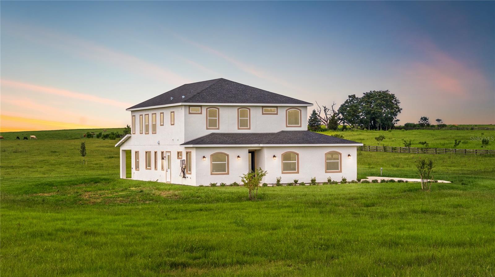 Welcome to this newly constructed Two-Story Custom-Built Estate nestled on 11 manicured acres of gently rolling pasture land (high & dry). This one-of-a-kind exquisite home spanning 4,599 total square footage harmonizes comfort, splendor, and serene countryside living all while being just 30 minutes from Ocala and the World Equestrian Center, 35 minutes to Crystal River, and 45 minutes to Gainesville. Enjoy renowned natural attractions such as Rainbow Springs, Devil’s Den, and Cedar Lakes all within 25 minutes of your doorstep. This 4 Bed/4 Bath rare masterpiece showcases an open-concept design, soaring ceilings, energy-efficient double-pane windows, and natural light pouring in from every direction—capturing breathtaking sunrises, sunsets, and panoramic views of grazing farmland. The Lower Level boasts 2,679 total sq.ft. featuring; a side-load 4-car garage, executive office (or optional 4th bedroom), guest bathroom, formal living room/dining room combo, private gym room, and covered lanai for year-round outdoor enjoyment. The gourmet kitchen is designed for the culinary enthusiast with custom cabinetry, gas range, and Quartz prep island. The walk-in pantry and laundry room combo includes a built-in pet bath station and laundry chute from the second floor. The Upper Level offers 1,920 total sq.ft. A stairway ascends from the kitchen to the en-suite bedrooms, and a large bonus/flex room. The owner’s suite offers a spa-inspired bath, separate vanities, walk-in closet, and scenic acreage vistas for the perfect personal retreat. French doors open to a balcony, offering sweeping views of the property. Beyond the enticing features, endless opportunities lie just beyond your front door. The property’s A-1 zoning allows for barns, accessory buildings, livestock, equestrian facilities, and a variety of agricultural uses—ideal for creating a horse farm, cattle operation, or your own private sanctuary. Your countryside paradise awaits! NO HOA, NO Flood Zone!
