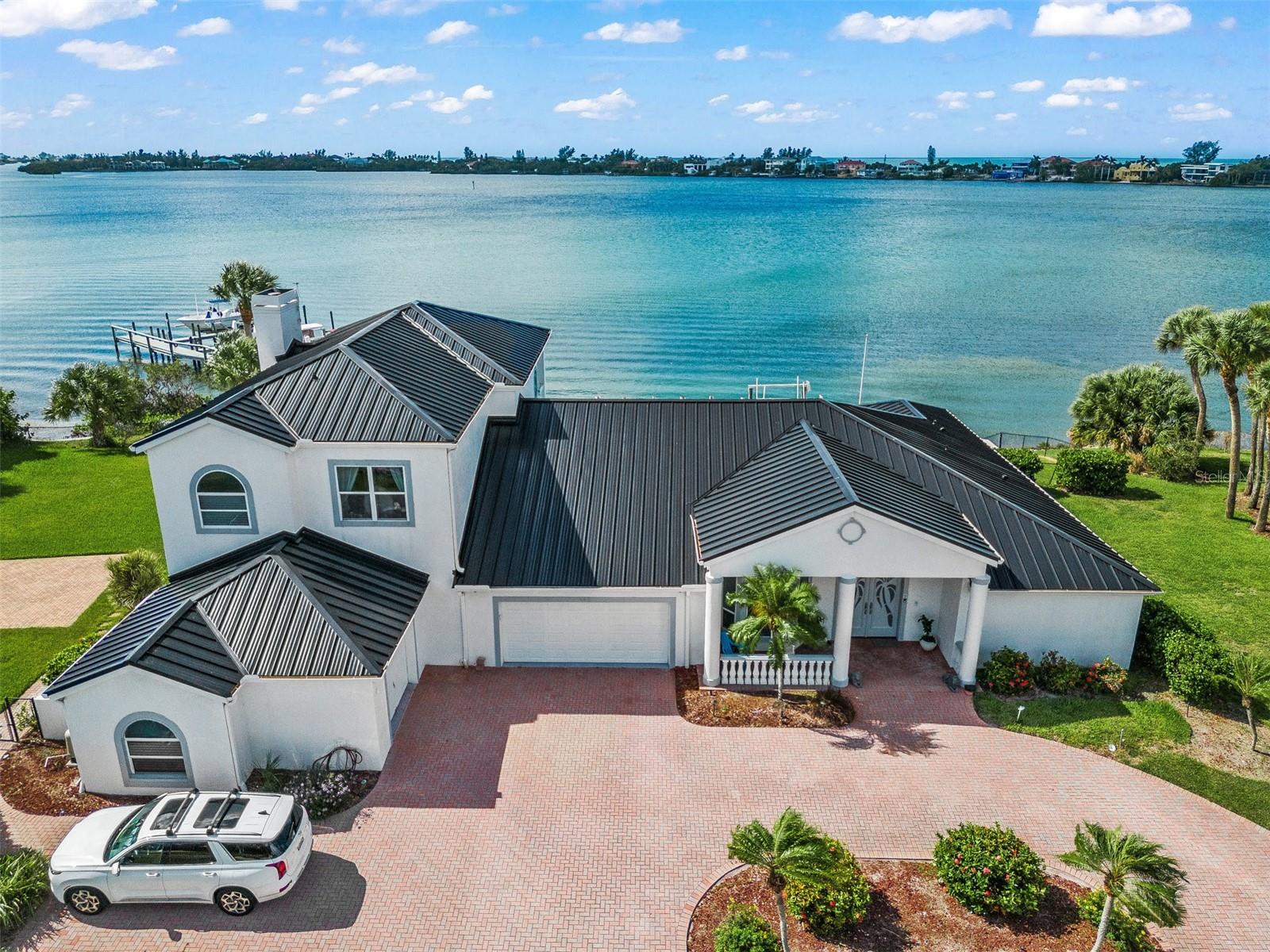 This exceptional island living boasts all the convenience of a mainland location. Prepare to be amazed by this newly renovated waterfront property overlooking the breathtaking Blackburn Bay. With its brand new aluminum roof, four HVAC systems, Kitchen Aid appliances, custom-made cabinets, and solid surface countertops, this home is the epitome of luxury. Step inside to find stunning marble flooring, exquisite electrical fixtures, and even a lift to the second floor. The abundance of built-in cabinets adds to the overall functionality and appeal of this property. Situated on elevated ground, this home offers incredible southern exposure, ensuring that every corner is flooded with sunshine and offers stunning views of Casey Key and Blackburn Bay. As you enter through the double custom doors, you'll be greeted by a grand foyer that leads seamlessly into an open floor plan. The spacious living room, dining room, custom kitchen, and family room all provide panoramic views of the magnificent Blackburn Bay. The attention to detail is evident in every room, with beautifully designed ceilings and elegant chandeliers adorning the dining room, living room, and family room. The family room, complete with a fireplace, custom cabinets, bar, and wine cooler, offers the perfect space for relaxation and entertainment. On the main floor, you'll find three generously sized bedrooms and two full baths, along with a huge laundry and utility room equipped with a second side-by-side refrigerator and a convenient powder room. The brand new lift will whisk you up to the second floor where you'll discover the master suite. This master retreat features a newly custom-made bathroom, three spacious closets, and wall-to-wall sliding doors that lead to a balcony overlooking the bay. Imagine sitting on the balcony, taking in the breathtaking view of the Blackburn Bay, and witnessing the countless activities of dolphins, passing boats, and mesmerizing sunrises and sunsets. It truly is the perfect way to complete your day. This property also offers two large open areas on either side of the house, providing ample space for various activities and hobbies. The prime location of this home offers easy access to both Sarasota and Venice, granting you the opportunity to experience the best of Southwest Florida's beaches. Whether you prefer the pristine shores of Venice or Nokomis, or the world-renowned Siesta Key Beach, all are within a short drive. Additionally, the highly regarded Pine View school for gifted children is just minutes away. With convenient shopping, easy freeway access, and a serene and secure environment, this property has it all.