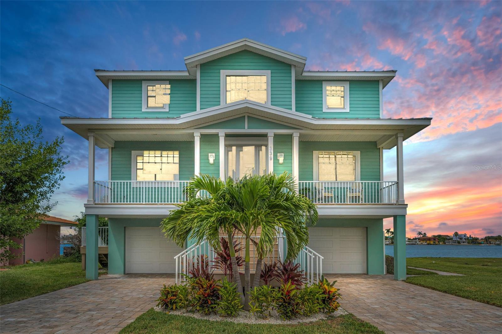 THE BEST OF BOATING AND THE BEACH, THIS BEAUTIFUL 5 BEDROOM, 4 BATH COASTAL CONTEMPORARY RESIDENCE FEATURES RARE FRONT AND REAR (NORTH AND SOUTH) WATERVIEWS, AND AN ASSUMABLE FLOOD INSURANCE POLICY THAT IS JUST $550/YEAR!  Feel the immediate coastal living vibe with your first step on the property of this home, an experience that will never grow old.  A dual entry brick paver driveway introduces a covered front porch with two separate sitting areas overlooking the waterfront.  Beyond the pleasing entry foyer, discover a home that feels virtually brand new!  Elegant wood flooring and rich detailed finishes provide a deeply satisfying living appeal.  Enjoy sweeping water views from the expansive great room and dining area.  The living room integrates an entertainment wall/LED fireplace with shiplap wall finishes.  Step out to the 39ft-wide covered deck and take-in dazzling panoramic views of the water; the huge deck presents three distinct sitting areas and offers access to the lower level.  Your designer chef’s kitchen will make your culinary experience a true joy - with exquisite quartz surfaces, exceptional shaker-style coastal cabinetry, high-quality stainless-steel appliances, lovely tile backsplash, pantry, a terrific island prep center with breakfast bar, and excellent waterviews.  Both of the first living level bedrooms are sizable and have their own waterviews, with bedroom one opening to the covered balcony.  The lavish full guest bath contains a rich quartz vanity, travertine tilework throughout, and a fabulous walk-in glass shower enclosure.  Your impressive upper level holds three spacious waterfront bedroom suites.  The superb owner’s suite includes a generously-sized walk-in closet with closet system, and private access to an inspiring 300sqft+ covered balcony with commanding views of the waterfront.  The gorgeous owner’s bath is luxurious, boasts two large/separate quartz vanities, a plush soaking tub encased in resplendent tilework, a sumptuous walk-in glass shower enclosure with two shower heads, and lovely water views.  The 2nd and 3rd bedrooms suites are large and beautiful, with graceful full baths (suite 2 opens to the upper-level balcony).  The lower level has two oversized garage spaces, and a large multi-purpose area ideal for fitness, gaming or storage.  The 300sqft covered lower-level deck overlooks the back yard and waterfront and is perfect for lounging and relaxing after a boating or beach day.  The updated seawall and composite dock with runway lighting have a step-down area for kayak/paddleboard launching. Dock supports a 13,000lb lift - from here you’re an easy 10-minute board ride to the Gulf!  Water filtration/softening system, epoxy garage flooring, posh finished 3-stop elevator and so much more.  An outstanding value in a truly uncommon location where all homes are on the water!  Just a 3-minute walk to the pristine soft white sands of TripAdvisors #1 rate beach, and a 5-minute walk to dining, shopping, entertainment!  All dimensions are estimates, buyer to verify.