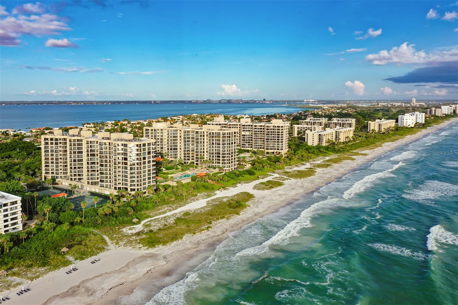 Welcome to The Water Club, one of the most unique communities on Longboat Key with space, privacy, and the ambiance of a resort on the beach and waters of the Gulf of Mexico. Your semi-private elevator opens directly into the foyer with views of the beautiful Sarasota Bay and Sarasota skyline through floor to ceiling glass. Open living spaces, well-appointed kitchen with breakfast area and the glistening Gulf beyond, along with three sunlit terraces create an exceptional indoor-outdoor lifestyle. This coveted southern exposure seventh floor condominium offers both sunrises over Sarasota Bay and sunsets over the Gulf and is being offered fully furnished. The residence has been designed by Marc—Michels Interior Design of Orlando and published for its remarkable sophistication. The designer is known for creating spectacular one-of-a-kind interiors for his discerning clientele including the public spaces of the new St. Regis resort on Longboat Key. As the homeowners you will enjoy two en-suite bedrooms plus den which could be a third sleeping space, and four full bathrooms all elegantly furnished. The private primary suite has his and her bathrooms, spacious walk-in closet w/built-ins and a private office area and sliding glass doors leading to a private terrace. Architectural columns, crown moldings, tasteful wallcoverings, lush window treatments including electric shades, built-ins, and marble designer flooring with 10’ ceilings throughout are just a few of the special features. The Water Club amenity package is superior to any other condominium on the key. Owning here gives you exclusive use of the beautifully designed 18,000sf renovated clubhouse, which provides residents with additional living and recreational spaces including a club room and billiard table, library with fireplace, ballroom and catering kitchen, 4 lighted Har-Tru tennis courts, junior Olympic heated pool and hot tub, spa and fitness center, security gate, climate-controlled storage, concierge services, on-site management, firepit, grills all located on 16-acre magnificent grounds. Located at the southern end of Longboat Key, residence is just minutes from exclusive St. Armand's Circle, the exciting waterfront of downtown Sarasota, and other cultural amenities of the city, minutes from award winning restaurants, Publix grocery store, CVS, the Longboat Key Club for golf, tennis and its restaurants and is only 20 minutes to the Sarasota airport. Water Club is a pet friendly community.