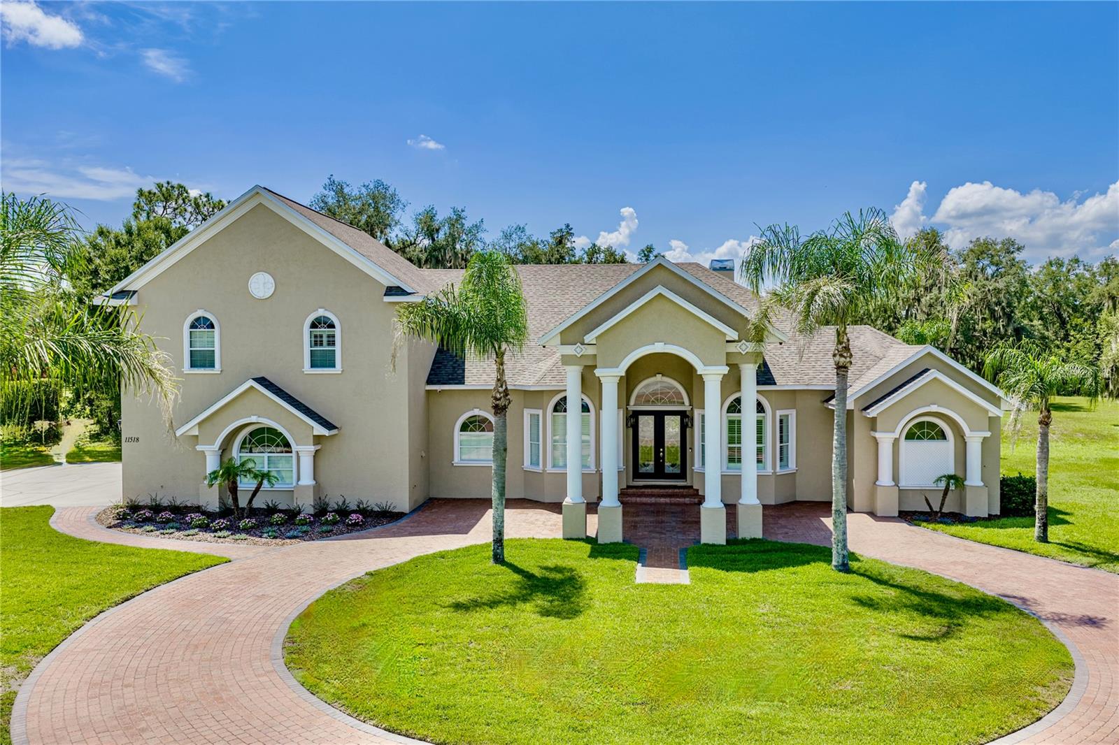 Welcome to Hammock Oaks Reserve, an exclusive gated enclave offering estate-style living on private 5-acre homesites just minutes from Tampa. Located in one of Hillsborough County's most sought-after school districts, this exceptional custom residence combines timeless architecture, luxurious amenities, and the privacy of country living with convenient access to shopping, dining, and major commuter routes.

This impressive two-story estate features 4 bedrooms, 4 full baths, 2 half baths, 4,722 square feet, heated pool & spa, pickleball court, and a spacious side-entry 3-car garage. A brick-paved circular driveway and elegant portico create a grand first impression, while double glass entry doors welcome you into an interior showcasing soaring ceilings, extensive crown molding, custom tile inlays, transom windows, plantation shutters, 8-foot doors, and designer finishes throughout.

The formal living and dining rooms feature double tray ceilings with crown molding and accent lighting, creating elegant spaces for entertaining. At the heart of the home, the refreshed chef's kitchen offers professionally updated cabinetry, stylish new light fixtures, granite countertops, a custom backsplash, built-in oven, gas cooktop with decorative hood, oversized prep island with sink, walk-in pantry, and breakfast bar seating for five. A frameless picture window in the breakfast nook captures beautiful views of the pool and backyard.

The kitchen flows seamlessly into the inviting family room featuring surround sound, custom wood accents, a built-in media center, double tray ceiling, and French doors leading to the outdoor living area.

The luxurious primary suite offers private lanai access, tray ceilings, plantation shutters, recessed lighting, and an impressive custom walk-in closet with built-in cabinetry, center island dresser, and designer chandelier. The spa-inspired bath features granite vanities, a soaking tub, elegant architectural details, and an oversized walk-in shower.

A standout feature is the expansive upstairs retreat with its own bedroom and full bath, making it ideal for multigenerational living, an in-law suite, guest quarters, a media room, home office, or private teenager's retreat.

Step outside to your own private resort featuring a sparkling saltwater pool, heated spa, expansive covered lanai, newer panoramic screen enclosure, and convenient pool bath. The beautifully maintained five-acre homesite offers exceptional privacy and recreation, including a professionally installed pickleball court. A detached 36' x 36' pole barn with electricity, water, and enclosed storage provides outstanding flexibility for a workshop, hobbies, recreational equipment, or additional storage.

Recent improvements include a new roof, new septic system, irrigation system, well pump, updated landscaping and sod, security camera system, refreshed kitchen, and modern lighting.

Hammock Oaks Reserve offers a rare opportunity to enjoy luxury estate living behind the gates while remaining just minutes to shopping, dining, recreation, and highly sought-after Newsome High School.

Experience the perfect balance of elegance, privacy, and modern convenience in one of the area's most distinguished gated communities. Schedule your private showing today.