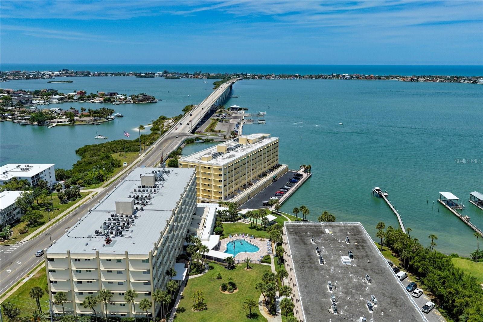 Welcome to Residence 506C in Harbour Club Building C, where breathtaking Intracoastal views create a spectacular daily backdrop of passing boats, dolphins, manatees, seabirds, and sparkling blue-green waters. This  2-bedroom, 2-bath condo offers 1,440 sq ft of comfortable coastal living with front-row seats to one of Belleair Bluffs’ most scenic waterfront settings. The kitchen is designed for both style and function, featuring granite countertops, real wood cabinetry, breakfast bar, dual pull-out pantries and spice racks, plus a full-size washer/dryer combo. Rich Brazilian Cherry wood flooring flows throughout the main living areas, complemented by neutral tile in the kitchen and baths. The spacious primary suite is filled with natural light and water views, complete with a custom walk-in closet and beautifully updated en-suite bath featuring dual vanities, granite counters, and a glass-enclosed shower with built-in bench. The open living and dining area includes a versatile office nook with a view, while the split floor plan offers privacy for guests. Additional conveniences include assigned under-building parking directly in front of your private storage unit. Harbour Club amenities include a heated waterfront pool, shuffleboard courts, grilling areas, clubhouse, and a waterfront dock overlooking the Intracoastal Waterway. Ideally located on the Belleair Causeway, residents enjoy easy access to beaches, shopping, dining, and all the conveniences of Belleair Bluffs. Location, views, and updates—this waterfront condo truly has it all!