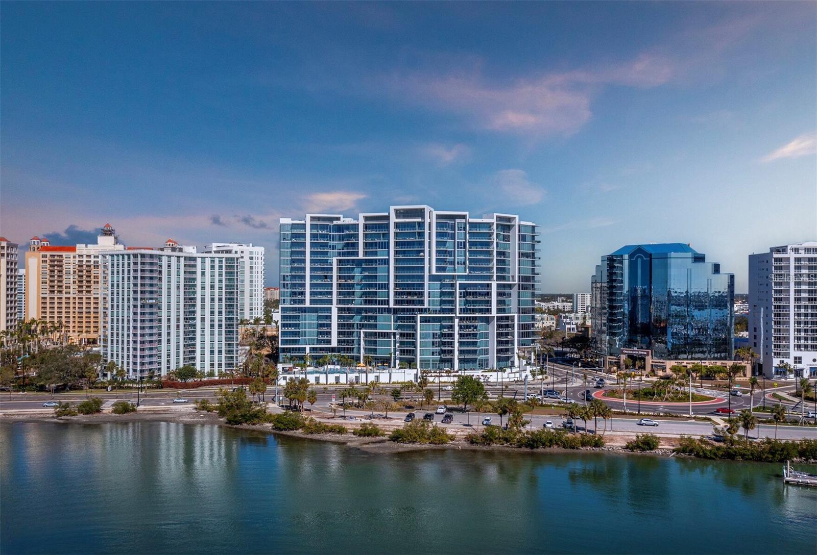 Numerous functional and design upgrades add significant value to this pristine, high-floor residence in one of Sarasota's most sought-after buildings. Positioned in a stack preferred for its through sight lines that showcase elevated vistas of both the waterfront and cityscape, this homes luxuries include large format porcelain tile flooring, motorized window coverings, premium custom cabinetry, custom built-ins in the living room and guest room, and designer lighting and fixtures throughout. With a layout ideal for entertaining and personal retreat, 1,770 A/C square feet encompass two large ensuite bedrooms as well as a separate den and powder bath and a dedicated utility and laundry room for added convenience. Private elevator access opens to a central vestibule and corridor that features spectacular, unobstructed views through floor-to-ceiling windows on either side of the residence. In the primary living space, the gourmet kitchen and dining area flow easily with the living room, all overlooking and opening fully to a deep private terrace with coveted southwestern exposure and marina views. Full-height windows and sliding glass doors create a seamless connection to the outside, expanding the living space with additional room for lounging and dining. Accentuated by a chic modern pendant, the dining area inside accommodates a table for six or more, with adjacent counter seating at the oversized kitchen island. Arranged for optimal prep and hospitality, the kitchen features premium appliances and finishes including stainless double-door refrigerator, range and hood, wall oven, integrated microwave, and a deep basin sink. Bespoke cabinetry and surfaces complement the homes elevated modern style. Past the great room, the spacious owners suite enjoys exquisite west-facing views through a wall of glass, with room for seating, dual closets with custom built-in wardrobe systems, and a spa-like bathroom with separate water closet, glass enclosed walk-in shower and an extra-long double vanity with cosmetic station. On the other side of the home, a large guest room enjoys an ensuite with soaker tub and floor-to-ceiling windows overlooking Downtown Sarasota. City views extend to the adjacent den, a generously sized flex space ideal for a media lounge, private office, or occasional hospitality. Beyond the interior, this unit has the considerable advantage as one of only six in the building with a parking space that can be equipped for EV charging. Located within steps of the waterfront at the heart of Downtown Sarasota, VUE is renowned for its resort-style amenities and gleaming modern features. From the notable service amenities including valet and concierge to the heated pool and spa with lounge areas, firepits, and grill station, and state-of-the-art fitness and resident lounges, this building offers a truly luxurious lifestyle. Furnishings available by separate offer for the ultimate convenience of turnkey acquisition.