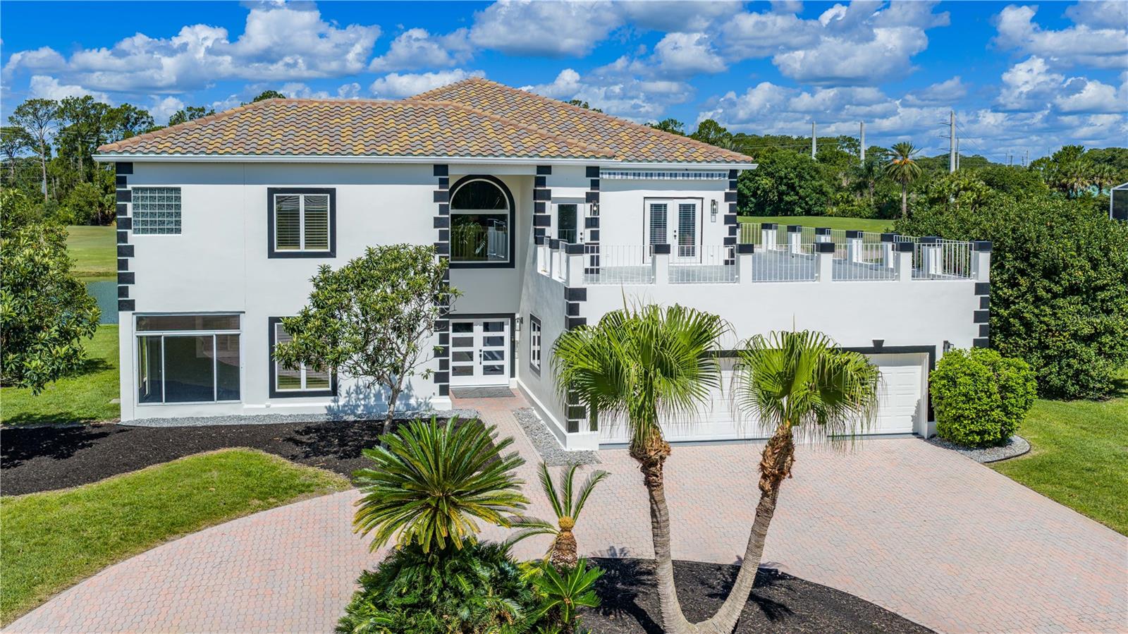 Welcome to 57 Bay Pointe, an exceptional estate offering panoramic golf course and lake views from one of the community’s most coveted locations. Extensively renovated throughout, this move-in-ready home combines luxury, functionality, and breathtaking scenery from multiple balconies and expansive living spaces. Featuring 4 spacious bedrooms, each with large closets and private en-suite baths, this home is ideal for both family living and hosting guests. Major updates include a newer tile roof, recently replaced AC systems, 2024 water heater with booster, freshly painted exterior, and Anderson windows and doors. A custom double-door entry opens to soaring ceilings, abundant natural light, and premium finishes throughout. The renovated kitchen is the heart of the home, showcasing quartz countertops, custom all-wood cabinetry with dovetail construction and soft-close features, designer tile backsplash, stainless steel appliances, and a large island perfectly positioned to enjoy the spectacular golf and water views. The family room features dramatic two-story ceilings, a wood-burning fireplace, built-in wet bar with beverage refrigerator, and French doors leading to the outdoor living spaces. Formal and casual dining areas offer ideal entertaining options with plantation shutters and updated flooring throughout. The main-level primary suite offers private lanai access, custom walk-in closet built-ins, and a beautifully renovated spa-inspired bath with dual quartz vanities, freestanding soaking tub, and oversized walk-in shower. Designed for today’s lifestyle, the home also features a dedicated office, flexible bonus room, and an upstairs loft overlooking the main living area. Upstairs, all three guest suites are oversized with en-suite baths, custom closet built-ins, and access to private or shared balconies. A renovated wraparound balcony with Shark Coating provides another stunning vantage point to enjoy the golf course and lake views. Additional features include a spacious laundry room with extensive cabinetry and utility sink, extended 3-car garage with built-in storage, irrigation system on well, and a paver circular driveway with outstanding curb appeal. Located within walking distance to the community’s amenities, including the new Founders Clubhouse, walking trails, and natural surroundings. Pool drawing available. Plantation Bay residents enjoy an optional membership lifestyle featuring 45 holes of championship golf, the $30 million Founders Clubhouse, resort-style pools, fitness and spa center, 9 pickleball courts, 10 tennis courts, dining, social events, and a secure guard-gated setting conveniently located near beaches, shopping, dining, and I-95. Buyers of this home receive a substantial discount on the club initiation fee. Ask listing agent for details. A rare opportunity to enjoy luxury living with unmatched golf and water views in one of the area’s premier communities.