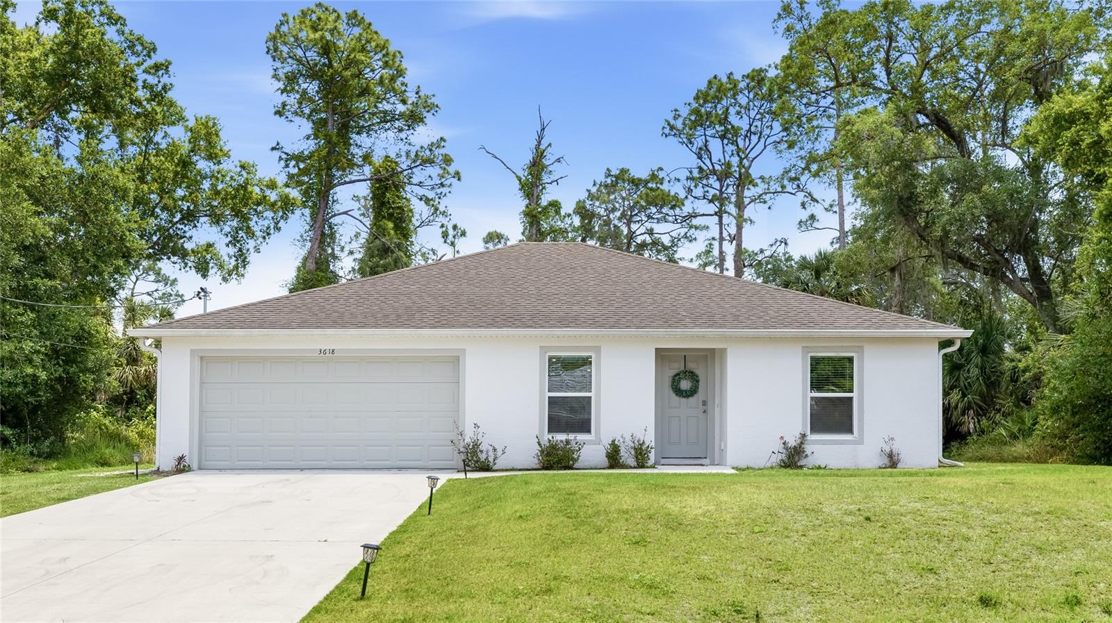 Welcome to this beautifully maintained 2022-built home nestled on a private lot with no HOA! From the moment you arrive, the clean white stucco exterior, manicured lawn, and landscape-lit driveway set the tone for what awaits inside. The open, flowing layout is filled with natural light and features luxury vinyl plank flooring throughout every room. The heart of the home is a well-appointed kitchen boasting white shaker cabinetry, stainless steel appliances, recessed lighting, and a breakfast bar peninsula perfect for casual dining. The kitchen flows seamlessly into the dining area and connects to the spacious living room, where sliding glass doors open directly to the backyard, bringing the outdoors in and making entertaining a breeze. The versatile sitting room off the foyer offers the perfect flex space for a home office, playroom, or reading nook. The primary suite features a generous walk-in closet and a private en-suite bath. Two additional bedrooms are well-sized with ample closet space and share a full guest bath. A dedicated laundry room and an attached two-car garage round out this thoughtfully designed floor plan. Out back, enjoy a large, private yard framed by a lush natural tree line of Florida pines, palms, and oaks, offering the kind of seclusion that's hard to find. Being a 2022 build, all major systems including the roof, AC, and water heater are just a few years old, giving buyers peace of mind for years to come. **THIS PROPERTY QUALIFIES FOR A 1% LENDER INCENTIVE IF USING PREFERRED LENDER. INQUIRE FOR MORE DETAILS.**