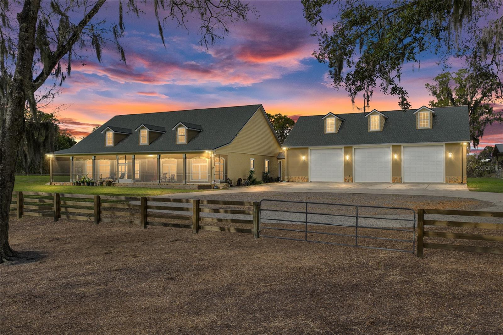 Morning coffee on the porch, sunsets by the pool, and wide-open acreage in every direction. This 10-acre Bellamy
Brothers Boulevard estate delivers the kind of farm lifestyle people move to Dade City for, with a sprawling home,
resort-style outdoor living, and the space to enjoy it all. A long private gated drive leads to a circular driveway and
the 40x60 garage, creating a grand and effortless arrival to this 3 bedroom, 3 bath 4000 + sq ft residence with a
brand new roof. From the expansive screened front porch, rocking chairs overlook the peaceful acreage where
sunrises stretch across the pasture and evenings settle into quiet country skies. Double front doors open to a living
space laid out to feel open and welcoming whether it's a quiet night in or a full house of guests. The floor plan
provides 2 spacious living rooms, a formal dining room, 2 dedicated offices, a split bedroom layout, and finishes that
give every nook and cranny a polished, elevated feel. High tray ceilings, wood-look laminate flooring and quadruple
sliding doors draw your eye straight to the lanai and outdoor living spaces beyond. The kitchen is designed to gather
around, featuring granite countertops, a central island with storage, a hammered copper basin sink, tile backsplash,
breakfast bar seating, a roomy pantry, and an eat-in dinette. A second oversized living space with triple sliding doors
offers endless flexibility for a billiards room, media lounge, or game room and a full bath for guests sits nearby. A
formal dining room framed by architectural columns and a tray ceiling provides an elegant space for holidays and
special dinners, while the office with double doors creates a quiet workspace. The primary suite is privately tucked
away and impressively sized at 19x31 ft, complete with its own sitting area, lanai access, double tray ceiling, and an
enormous walk-in closet with built-ins and a vanity station. The en suite bath features a soaking tub, dual granite
vanities, a walk-through shower, and private water closet. On the opposite side of the home, bedrooms two and three
are generously sized and share a full bathroom with a tub/shower combo and dual sinks. Outside is where this
property truly shines. The screened lanai opens to a 20x40 sports-style pool with beach entry and an expansive paver
deck designed for relaxing and entertaining. The 40x20 outdoor kitchen and bar feels more like a private resort with
seating for 10+, a built-in grill, sink, refrigerators, and a covered lounge area. The land itself is fully fenced and
cross-fenced with two pastures and is zoned agricultural, ideal for animals and farm life- the donkeys and chickens
might even decide to stay! A 40x60 garage/shop (with three large 12’ bays, a finished and temperature controlled
office, and approximately 52x16 ft of insulated attic storage), a 60x40 pole barn, storage sheds, and additional
covered pen provide plenty of room for equipment or livestock. Here, days begin with sunrise views across the
pasture and end with friends gathered around the pool under the stars. Properties like this rarely come available
along Bellamy Brothers Boulevard. Schedule your private showing and experience it for yourself today.