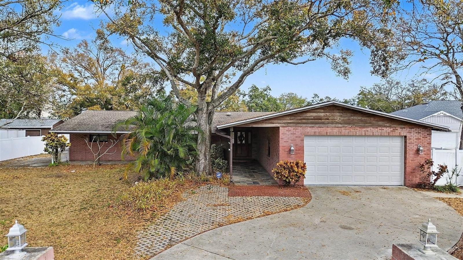 **MOTIVATED SELLER - BRING YOUR OFFERS** MORE SPACE. MORE FLEXIBILITY. MORE VALUE.   
If you’ve been waiting for the right combination of space, layout, and opportunity — THIS IS IT. Situated on OVER A 1/3 ACRE beneath majestic oak trees & framed by a charming white picket fence, this property offers the kind of flexibility that’s getting harder to find — now at an even more compelling price. 
Start your day on the expansive COVERED L-SHAPED FRONT PORCH, where mornings feel slower and more intentional. Inside, 2,338 HEATED SQ FT unfolds in a thoughtfully designed SPLIT FLOOR PLAN that balances everyday comfort with room to gather. A welcoming formal living area greets you at the entry, while the impressive 20’ x 23’ FAMILY ROOM becomes the natural heart of the home — perfect for hosting, relaxing, and everything in between.   
Designed for true Florida living, 2 Sets of Patio doors seamlessly connect the interior to both a SCREENED SUNROOM & a PERGOLA-COVERED PATIO, creating effortless indoor-outdoor flow. The dining area, complete with built-in buffet and cabinetry, offers both charm and functionality, while the kitchen delivers with SOLID WOOD CABINETRY, STAINLESS STEEL APPLIANCES INCLUDING A DOUBLE OVEN, abundant storage, and durable VINYL WOOD-LOOK PLANK FLOORING throughout the main living areas.
One of the most valuable features of this home is the presence of 2 SEPARATE PRIMARY SUITES — each with its own UPDATED BATH — offering flexibility for multi-generational living, guests, or evolving lifestyle needs. Two additional bedrooms and a THIRD UPDATED BATH provide even more options for family, visitors, or work-from-home setups.
Just beyond the garage, you’ll find an additional 370 SQ FT FLEX SPACE — ideal for a home gym, studio, hobby room, or even future income potential.
Step outside into your PRIVATE BACKYARD RETREAT, where multiple outdoor living areas invite you to unwind or entertain. Enjoy evenings on the screened lanai, gather under the pergola, or relax around the fire pit. The expansive yard offers room to garden, play, or store the toys that support your lifestyle.
The OVERSIZED GARAGE WITH WORKSHOP SPACE (WITH ELECTRIC), EV CHARGER, and ADDITIONAL PARKING PAD provide exceptional space for BOATS, RVs, or recreational vehicles — something rarely found at this price point.
Key updates include ROOF REPLACED IN 2021 and NEW WATER HEATER (2023). Conveniently located just 15 MINUTES TO ST. PETE/CLEARWATER AIRPORT and approximately 25 MINUTES TO TPA OR THE BEACHES.
This is more than a home — it’s a property that adapts to your life, your needs, and your future. And now, with its new pricing, it’s an opportunity you don’t want to miss.