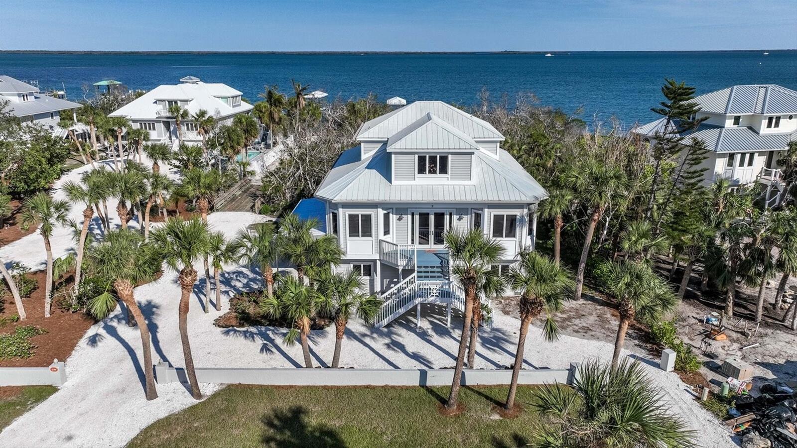 Under contract-accepting backup offers. A truly exceptional waterfront estate offering approximately 2,300 square feet of refined coastal living, this residence enjoys over 100 feet of coveted frontage on Gasparilla Sound with a private dock, covered boat lift, and deep-water access in the serene setting of Peekins Cove. Built in 2006 by Bowen Construction, the home showcases thoughtful craftsmanship with impact windows and doors, elevator-ready design, and two beautifully appointed living levels. The main level is designed for effortless entertaining, featuring two guest suites with private en-suite baths, an open-concept kitchen overlooking the living and dining areas, a laundry room, and tile flooring throughout. The living and dining spaces are filled with natural light and accented by tray ceilings, recessed lighting, and elegant crown molding. A spacious covered deck extends from the living area, providing the perfect vantage point to take in stunning sunrises over the harbor and tranquil water views. The kitchen offers solid wood cabinetry, Corian countertops, stainless steel appliances, an ice maker, and ample storage, ideal for both everyday living and hosting guests. Upstairs, the primary suite serves as a private sanctuary, complete with a generous bath featuring dual vanities with granite countertops, abundant storage, a jetted soaking tub, and a walk-in closet. A private deck off the primary suite captures sweeping views of Peekins Cove and Gasparilla Sound, while the adjacent loft offers flexible space for a sitting area, office, or reading retreat. An oversized 1,560-square-foot climate-controlled garage provides exceptional space for multiple vehicles, golf carts, and water toys. The property also offers room to add a pool, enhancing its resort-style potential. Offered fully turnkey, this exceptional waterfront home delivers a rare combination of privacy, craftsmanship, and premier boating access on Gasparilla Sound.