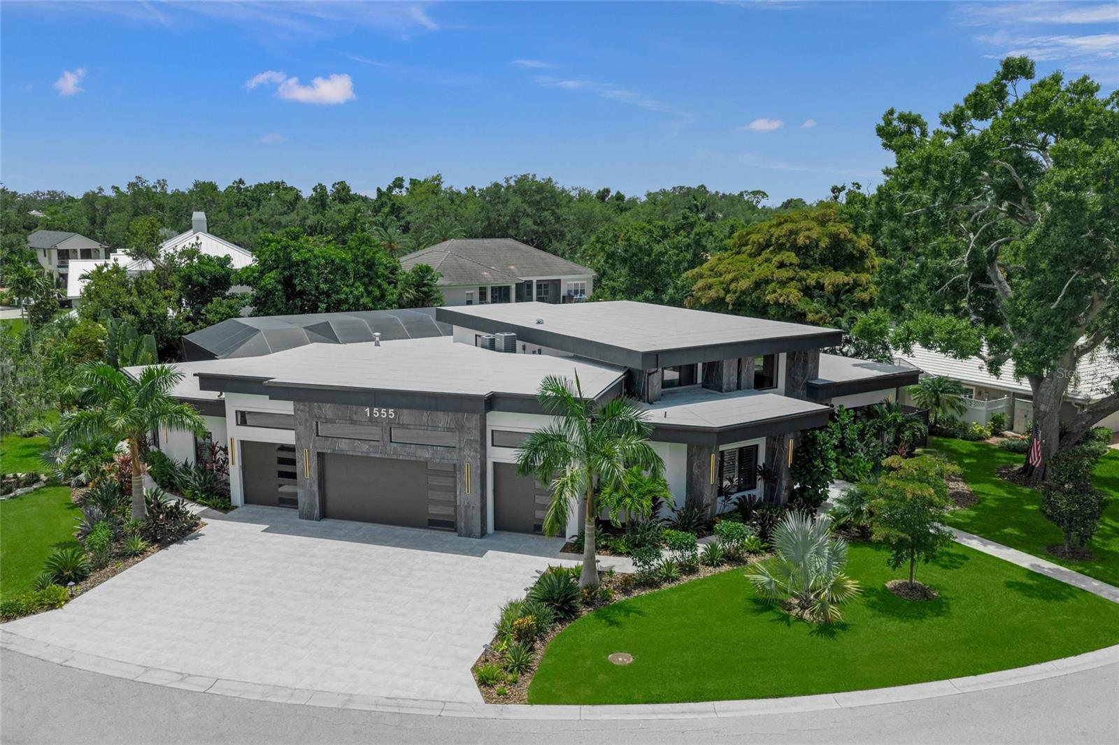 Modern architecture reaches an extraordinary new level at 1555 Eastbrook Drive, a newly completed 2025 estate offering nearly 4,000 square feet of sophisticated single-level living in one of Sarasota’s most coveted residential corridors. Positioned on an expansive 0.45-acre homesite near Oyster Bay and the sought-after West of Trail area, this five-bedroom, five-and-one-half-bath residence was created for the discerning buyer who values distinctive design, advanced technology, privacy, and effortless entertaining.

Beyond its dramatic contemporary façade, soaring ceilings, expansive glass, warm architectural woodwork, and statement lighting create an atmosphere that is both impressive and inviting. The designer kitchen commands attention with custom flat-panel cabinetry, premium appliances, elegant stone surfaces, and an oversized waterfall island that opens seamlessly to the grand living and dining spaces. Integrated smart-home automation, generator, whole-home audio, surveillance, and dedicated controls place lighting, sound, and security at your fingertips.

The primary suite is a private sanctuary with direct access to the pool, dual custom walk-in closets, and a spa-inspired bath featuring a sculptural soaking tub, dramatic stonework, dual vanities, and an oversized glass-enclosed shower. Four additional bedroom suites offer beautifully appointed private baths, creating exceptional accommodations for family and guests. A rare four-car garage with soaring ceilings provides space for an impressive automobile collection, with the potential for lift systems and additional storage.

Designed to rival a private resort, the expansive outdoor retreat features a heated saltwater pool, elevated spa, illuminated water features, panoramic screen enclosure, and lush tropical surroundings. The covered lanai is finished with wood-accented ceilings and dramatic stone surfaces, while the fully equipped outdoor kitchen, wet bar, and generous gathering areas make year-round entertaining effortless.

This exceptional Sarasota luxury home places Siesta Key’s celebrated quartz-sand beaches and vibrant village atmosphere within easy reach. Enjoy convenient access to the historic Field Club, Southside Village, Sarasota Bay, downtown Sarasota, St. Armands Circle, Marie Selby Botanical Gardens, fine dining, designer shopping, boating, golf, and the city’s renowned arts and cultural venues. More than a residence, 1555 Eastbrook Drive is a statement of modern luxury in an irreplaceable Sarasota setting.