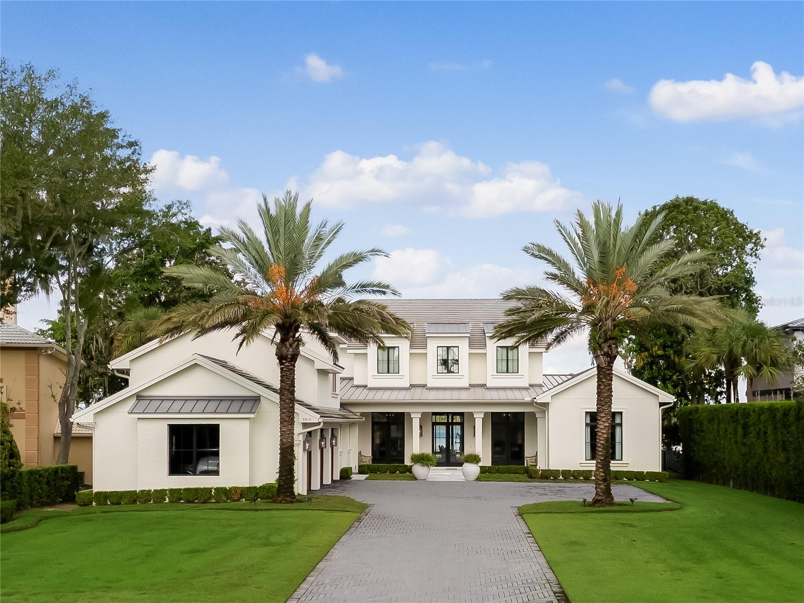 Welcome to your urban sanctuary! This nearly New, luxurious home on Lake Tibet on the Butler Chain of Lakes offers the perfect blend of elegance and convenience, just minutes from shopping and dining on “restaurant row.”

Built by Maroon Fine Homes and completed in late 2020, this residence is nestled in the premier gated Bay Point community, under a mile from Bay Hill Country Club. Outdoor amenities include a large pool, hot tub, outdoor kitchen, and a covered dock with lifts for a pontoon and jet skis. A concrete-capped seawall ensures protection for the property.

Custom-built with the highest quality materials, this home showcases exquisite designer elements, including Ralph Lauren outdoor lighting and custom wallpaper. The exterior features timeless light painted brick and oversized windows, providing stunning views of Lake Tibet.

Step inside to an open floor plan, highlighted by a spacious kitchen with double oversized islands that seat eight, plus a custom-built banquette for ten. The living areas boast floor-to-ceiling lake views, perfect for entertaining, while the living room features soaring 12-foot ceilings and a custom stone fireplace. The main level includes a cozy movie lounge, a large office with built-ins and a custom barn door, and a grand foyer with impressive windows. The primary suite offers cathedral ceilings and breathtaking lake views, ideal for enjoying sunsets and Disney fireworks. This floor also has a guest ensuite, a laundry room, two powder rooms, and ample storage.Upstairs, a landing with a desk/study area leads to two ensuite bedrooms, both with access to the upstairs patio, and a flexible room that can serve as an additional bedroom or media room. The back stairway, accessible from the 3.5-stall garage, features a state-of-the-art workout room and a charming reading nook, along with a steam shower bathroom.

This home is equipped with health-conscious features, including whole-house water filtration and UV furnace filters. With its prime location and luxurious finishes, this is a must-see for the discerning buyer seeking a truly exceptional property on the Butler Chain of Lakes. There just isn't any other lakefront home out there today that compares in quality and Location.