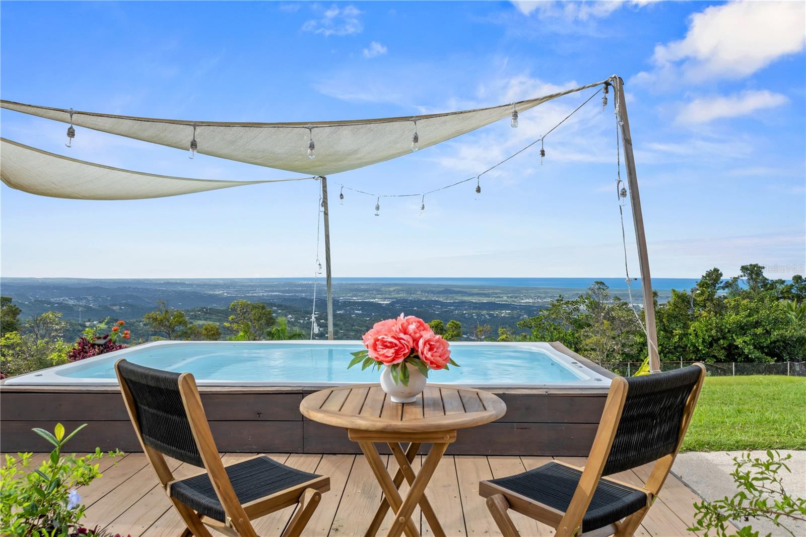 "The Sky House" is situated within a private, gated community, offering over one acre (4,126 square meters) of carefully maintained grounds that ensure privacy and security. The residence, featuring three bedrooms and two-and-a-half bathrooms, is adjacent to El Yunque Rain Forest and provides sweeping, unobstructed views across the Atlantic Ocean, mountains, valleys, and San Juan city. Despite its tranquil and secluded setting, the property is conveniently located only 30 minutes from SJU Airport and San Juan.
A 25-minute walk along a wide jungle path leads to a sizable, discreet swimming hole, fed by a river and bordered by natural boulders. Within five minutes’ drive, residents can access several rivers, hiking trails, waterfalls, and additional swimming sites. The nearby country road connects to renowned oceanfront golf resorts, premium accommodations, dining venues, bars, and beaches along the north shore. This residence presents a distinctive living or investment opportunity. Owner financing available