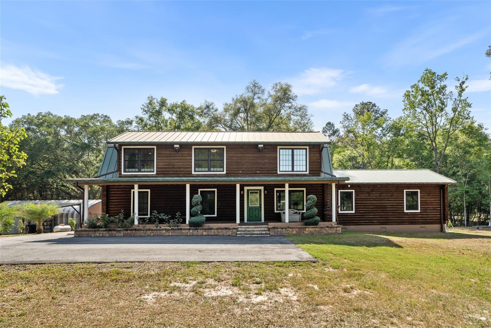 Looking for an updated home on a gated, 5 acre parcel walking distance to the town of tioga? You found it. Opportunities like this are extremely rare. This unique  
4 bedroom, 2.5 bath modern log cabin styled home is for the outdoor enthusiast and has everything you could need, including a square foot workshop, a dedicated boat storage / washing area, multi car carport, a fire pit, massive full length screen porch and outdoor kitchen… and we haven’t even made it inside. 

As you walk up the covered front porch through the front door you’ll immediately notice the quintessential pine log walls and cathedral ceilings. The spacious living room leads to the dining room which is perfectly situated between the remodeled kitchen and massive, 600 square foot bonus room. The kitchen is complete with real wood cabinets and updated quartz counter tops.

Two bedrooms, a full bathroom, and the laundry room are also located on the first floor. Upstairs you’ll find a spacious light-filled loft overlooking the living room and leading to the expansive primary suite and bathroom, as well as another bedroom.

As you step onto the 750+ square foot screened in porch, you’ll find a fully equipped outdoor kitchen including an oven & sink. But that’s not all, as you leave the screen doors, you’ll find a large wooden deck and a beautiful paved patio featuring a fire pit and surrounded by gardens all overlooking acres of private property.

Just steps from the home you’ll find a carport large enough for 3 cars, an RV hookup, a boat storage areas, a 1200 sqft metal workshop with electricity, water, multiple additional open storage areas, and a private half bath, perfect for all of your toys and any project you can dream of. 

Other features include: Clay Electric (low electric bills…NO GRU!!), one well, one septic tank, and a propane tank. A 15KW generator with manual transfer switch controls 2/3rd of the home, battery back up lighting in the kitchen and upstairs hallway. A mini split (2023) is located in the primary bedroom keeping it extra cool at night. There’s also an outdoor tankless continuous loop water heater, leaf filter gutter system and a whole house water softener. 

DO NOT miss this rare opportunity to live the perfect country lifestyle, minutes from Tioga, Publix, restaurants, schools, and less than 30 minutes to UF. Call today to schedule your showing while you can.