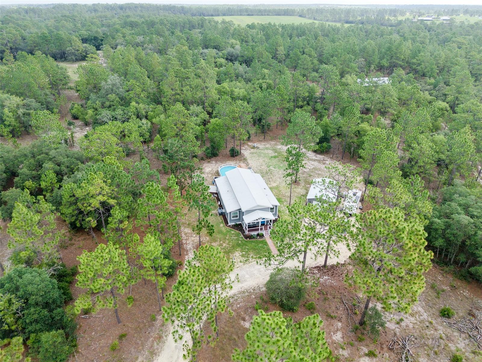 They Said Find Five Acres with a Pool, a Garage, and Room for Your Horses. We Found It.

Welcome to a property that checks every box on the rural Florida wish list — and then builds you a screened lanai to celebrate.
Can't make it out in person yet? Walk the entire property — inside and out — with our full 360° virtual tour, linked.  Tour every room and every acre before you ever set foot on the property.

This one-of-a-kind 3-bedroom, 2-bath container-built home sits on 5 fully usable agricultural-zoned acres in Levy County, where your nearest neighbor is far enough away that the only thing you'll hear in the morning is your own livestock. Bring your horses, your chickens, your goats — the land is ready.
The home itself is anything but ordinary. Built from structural corten steel — the same material engineered to cross oceans and survive what Florida weather throws at it — this is a home built to last!  Inside, approximately 1,200+ square feet of thoughtfully finished living space delivers comfort without compromise.

Step outside and the property keeps delivering: an above-ground pool with deck for those brutal Florida summers, a covered front porch for your morning coffee, a screened lanai for evenings without the bugs, and a garage/outbuilding ready for equipment, tools, or whatever your rural lifestyle demands.

Property Highlights:

3 Bed / 2 Bath | ~1,200+ sq ft
Corten steel container construction — hurricane resistant, termite proof, mold resistant
5 acres | Agricultural/Rural zoning — horses & livestock welcome
Above-ground pool with deck
Screened lanai + covered front porch
Garage/outbuilding
Full 360° interior and exterior virtual tour available
Levy County — wide open space, low taxes, no HOA

This is a property for the right person — and that person is going to know it the moment they pull down the driveway (or the moment they press play).