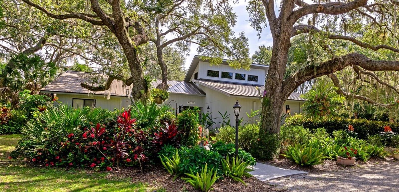 Discover your own acre of paradise in the serene Hidden Oaks community! This charming country estate, set on a spacious 1-acre lot, offers tranquility with a lake and community tennis courts just across the street and no neighbors to the south. A circular driveway and side-entry garage provide ample parking, while the custom speakeasy front door with sidelights welcomes you into a stunning interior.

Step into the great room, where 15-foot vaulted ceilings and a cozy wood-burning fireplace create an inviting atmosphere. Sliding doors in the great room and foyer disappear for seamless indoor-outdoor entertaining, opening to a screened paver lanai and sparkling pool. The gourmet kitchen is a chef’s dream, featuring custom cabinetry, granite countertops, an 8-foot island with bar seating, premium appliances, and a built-in desk in the breakfast nook.

Hardwood floors are throughout the living area. From the entry foyer, a hallway leads to three bedrooms—one currently a den—and a full bathroom. The master suite, with direct pool access, boasts a luxurious full bathroom and walk-in closet. An additional bedroom, now a media room, and another full bathroom with pool access complete the main level. Crown molding adorns every room, adding elegance throughout.

Upstairs, a versatile loft serves as an office, craft space, or playroom, with access to an air-conditioned 8x20 storage area. The nearly 600-sf side-entry garage is a standout, featuring an oversized 18-foot door, an 8x6 work area, polyaspartic flooring, and a dedicated split A/C system—perfect for car enthusiasts or hobbyists. The front porch and sidewalks, also finished with low-maintenance polyaspartic coating, enhance curb appeal.

A 2021 metal roof with skylights brightens the covered lanai, while the beautifully landscaped grounds, dotted with oak trees and vibrant orchids, create a picturesque setting. The one acre home site is a Florida Certified Wildlife Habitat. The pool cage was replaced in 2024.

Located just 4.6 miles from downtown Sarasota and 6 miles from pristine beaches, this Hidden Oaks estate blends country charm with urban convenience. Embrace the best of both worlds in this meticulously designed home, complete with a pool and stunning natural surroundings. Your private paradise awaits!