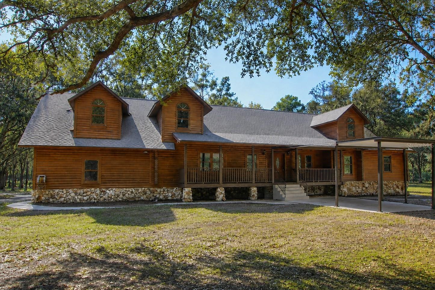 Virtually Staged. PRICED BELOW APPRAISED VALUE! Discover the peaceful elegance of this beautifully crafted cypress log cabin, nestled on a private and fully fenced 6.11-acre retreat in Sorrento, FL. Offered for the very first time, this truly distinctive 4,067 SF home combines timeless rustic appeal with refined modern comfort, showcasing five generously sized bedrooms, each featuring its own private bathroom for exceptional convenience. One upstairs bedroom and one downstairs bedroom do not include built-in closets. Step through the welcoming entry to discover Australian Pine flooring flowing throughout, while the downstairs primary suite features rich Walnut flooring, dual walk-in closets, and a luxurious ensuite with a garden tub and walk-in shower. The centerpiece of the home is the inviting living room, highlighted by an impressive stone wood-burning fireplace. Cooking enthusiasts will appreciate the country-inspired eat-in kitchen complete with extra-thick granite countertops and 42" solid wood cabinetry. Sharing the fireplace, an additional sitting room opens to an expansive 8’x40’ covered rear deck, ideal for enjoying Florida’s relaxing outdoor atmosphere. Extending from a spacious upstairs bedroom, a custom-built walkway leads to a flexible landing presently serving as a billiards/game area and a second primary suite featuring its own walk-in closet and full bath. Additional functional features include an interior laundry room with a half-bath connecting to an oversized 3-car garage. Lovingly maintained, the home was elevated 3 feet for durability and includes a New Roof installed in July 2025, freshly sealed exterior and pest treatment completed in 2025, a New Hot Water Heater in 2025, dual A/C systems from 2022 and 2019, and a New Drain Field added in 2020. Zoned A-1 with no HOA, this property offers endless possibilities for an accessory dwelling, gardening, horses and farm animals, or even a boutique Bed & Breakfast with special exception approval. Experience unmatched tranquility and privacy while remaining just minutes from the 429, Mount Dora, Orlando, and Florida’s renowned beaches. This extraordinary one-owner cypress retreat is truly one-of-a-kind — schedule your private showing today!