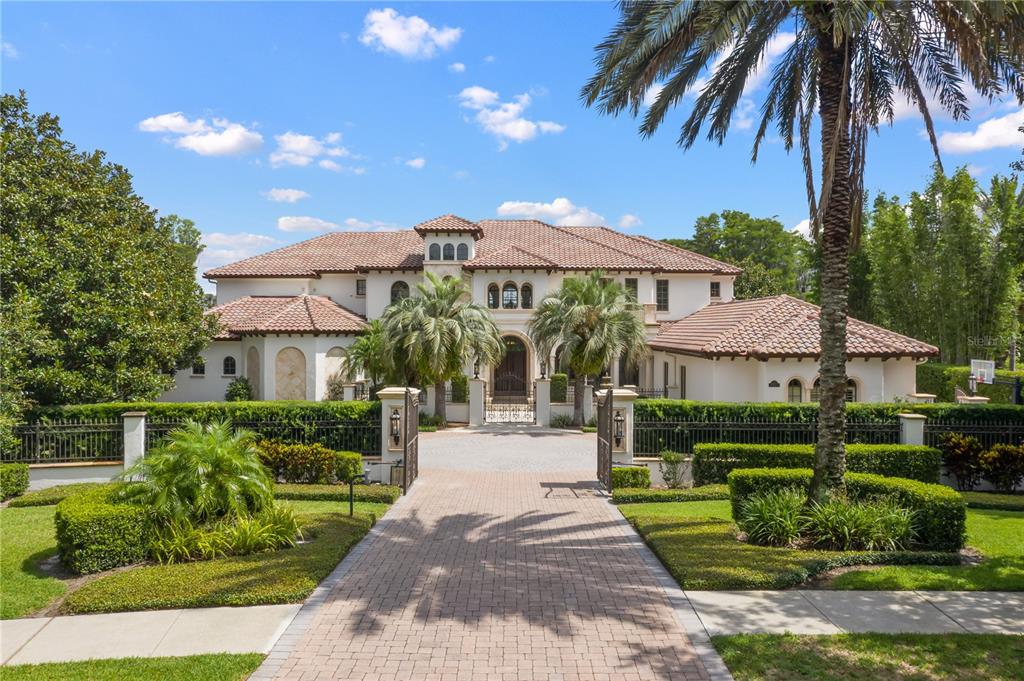 Exquisite Mediterranean masterpiece, located in the 24-hour guard-gated community of Lake Butler Sound. This stunning residence features over 10,000 square feet of luxury living space and is perfectly positioned along the shores of Lake Butler on the famed Butler Chain of Lakes. This privately gated compound includes a resort pool with rock waterfalls, a lazy river, hot tub, summer kitchen and an outdoor living room with a gas fireplace. As you step through the front doors, your eyes are immediately greeted by soaring two-story ceilings and a wall of arched windows overlooking the pool and lake. Luxury and elegance resonate throughout the home with exquisite details that are truly second to none. The gourmet kitchen features a massive center island, top-of-the-line appliances, a double Sub-Zero refrigerator and a hidden pantry. The primary suite features a separate sitting area, two massive closets with custom cabinetry, and a spa bath with exquisite marble and onyx tile, a jetted tub, and oversized walk-in shower. There is also a first-floor home theater, massive game room, private wine cellar, fitness room and a home office/library. On the second floor, you will find a large outdoor balcony and three additional bedrooms, each of which would be considered an owner’s suite in any other home. With over 432 feet of shoreline and a private boat dock with a boat lift, there is sure to be endless hours of fun on the water. The car enthusiast will love the expansive motor court with a four-car garage and for the tech aficionado, the home is fitted with the state-of-the-art technology and home automation. This former celebrity-owned home is located just minutes from fine dining, world-class shopping and all of the area theme parks, the location of this spectacular residence simply can’t be beaten.