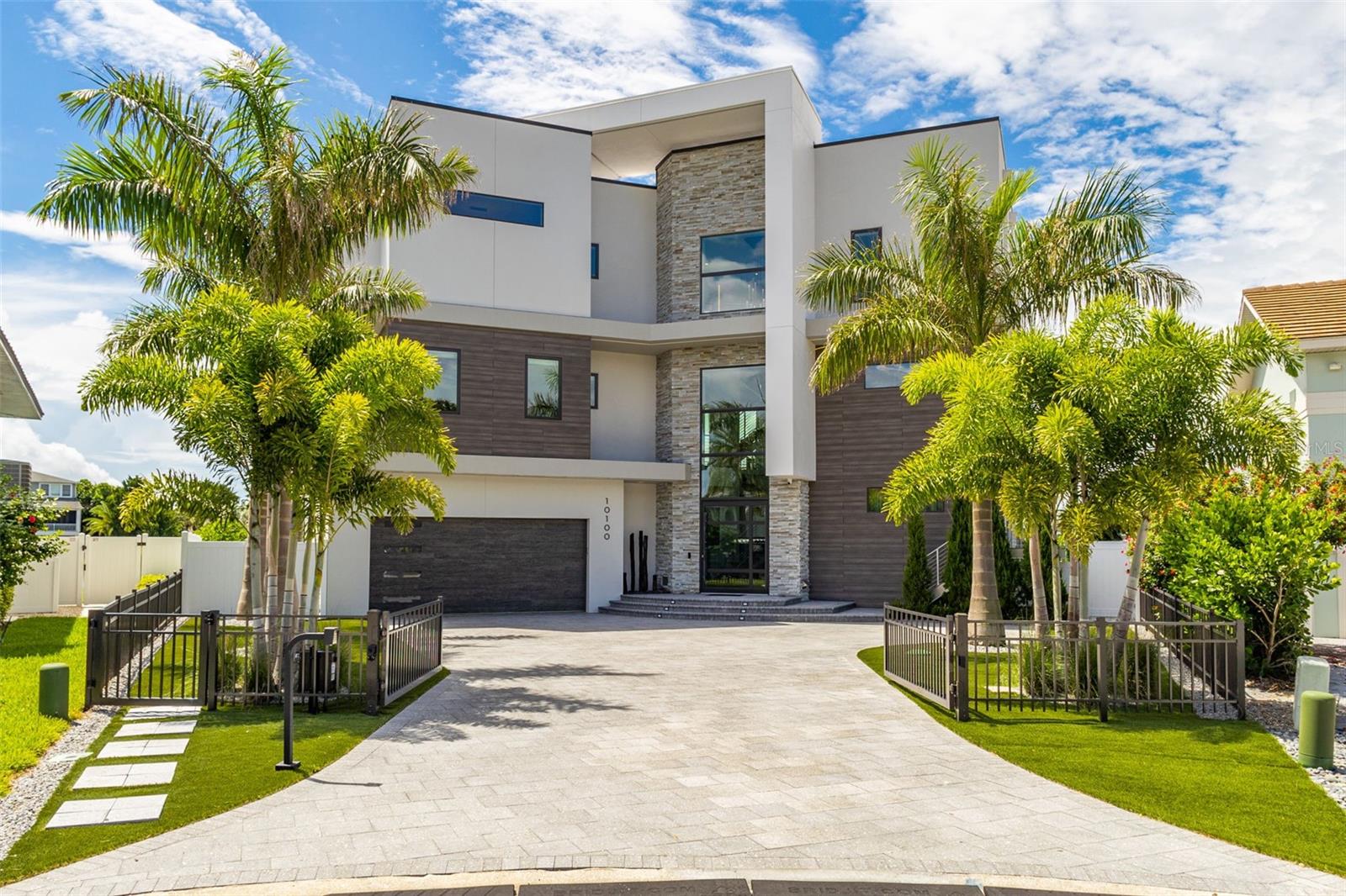 Paradise Island in Treasure Island. The epitome of contemporary luxury awaits you. This stunning custom estate was built new in 2022 and sits on 127ft. of open water. The home has four bedrooms all with en-suite bathrooms, one half bath, a four car tandem garage, an in-ground swimming pool and 4,066sf. of living area. This exquisite masterpiece has three levels of everything you could ever wish for, want or need and so much more. The main living level offers a soaring two-story great room with living and dining areas, a 74in. linear gas fireplace with multiple color schemes, an Italian Luceplan chandelier and spectacular water views. The kitchen is equipped with Wellborn Luxe Series high gloss cabinetry, granite countertops, a recessed ceiling over a 9ft. island, Sub-Zero refrigerator/freezer, Wolf gas cooktop, double oven, warming drawer, microwave drawer, and Cove dishwasher. A beverage center with Marvel wine cooler, beverage cooler, ice maker, and a butler's pantry with a Thermador coffee/espresso machine add to the luxury. The third level spacious primary suite offers breathtaking water views, two walk in closets, his and hers vanities with Wellborn Luxe cabinetry, solid surface Corian counter tops, dual showers, and a soaking tub. The guest suite along with the other two bedrooms all have walk in closets, Wellborn Luxe cabinetry and solid surface Corian counter tops. The 44ft. Pebble tech Pool has an in ground spa, Sun shelf, Travertine pavers, three water bowls with color changing lights and a Pentair heat pump with heat/cool functionality. The dock built in 2018 has a 25K boat lift and a 6K lift all made with Poly decking. There are additional pilings for large boat docking as well. The exterior offers a stucco finish with Boral Cultured stone and Trespa Pura flush siding from the Netherlands (zero maintenance required). The windows and sliders are all CGI Sentinel Aluminum Clad and impact-resistant. The roof is a commercial grade SBS modified Bitumen with 20 year warranty. The landscaping consists of lush Florida Foliage, 2,000sf of Artificial turf, irrigation system, landscape lighting and speakers, and a water fountain with ancient volcanic rock formations. Other features include: Three story floating staircase with Red Oak Treads/landings and powder coated railings, an 8ft. X 6ft pivoting glass entry door, a three story foyer with Grand 31- Light Avenue Lighting Alpine chandelier, Venetian plaster on foyer and kitchen walls, kitchen ceiling, and primary bedroom accent wall, large white high gloss Porcelain tile throughout, an elevator with telephone and emergency alarm, two laundry rooms with with steam washer and dryers, San Rafael 8ft. Interior doors imported from Spain throughout, Hunter Douglas window shades throughout, custom draperies, music speakers throughout, 12 security cameras, color-changing lighting in walls and ceilings throughout, Square one-piece Kohler Toilets, Nine Smart Tv’s inside and two outside, two tankless gas hot water heaters and a 500 gallon LP tank, four Trane HVAC systems with anti-corrosion treatment with warranties through Apr-2032, and a newer seawall. The home's systems, including lighting, sound, cameras, alarm, window shades, HVAC, and pool, are controllable via an app. With such unparalleled features and water views from every angle this property truly stands out. The overall location is only minutes to the Sandy white beaches of the Gulf of Mexico, fine dining, shopping and so much more.