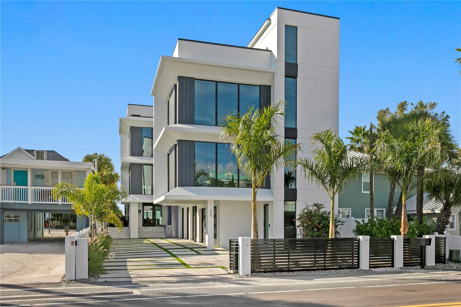 Modern sophistication meets exceptional beachfront living in this new construction coastal estate. Designed for refined living and effortless entertaining, the residence offers expansive light-filled interiors, panoramic beach views, elegant finishes, and a dramatic rooftop terrace atop the main home. With 9,271 AC sq ft combined, the property includes a Main House with 7,440 AC sq ft and an attached Guest House with 1,831 AC sq ft, each with its own private entrance (per builder plan). The estate features 8 bedrooms total, with the main residence offering 6 bedrooms, 6 full baths, and 2 half baths, and the guesthouse offering 2 bedrooms, 2 full baths, and 1 half bath. Luxury appointments include a residential elevator, automatic sliders on main level, floating staircase, wine cellar, a combined theatre and golf simulator room, game room, custom-built closets, and a smart home audio system with integrated in-wall touchscreens. Full retracting glass doors connect interior living spaces to multiple terraces overlooking the beachfront setting. The main level features imported Italian porcelain flooring, an entertaining bar, gym with sauna, and a guest suite or office, all opening directly to the resort-style pool and coastal surroundings. The second level offers elevated ceilings in the dining and living areas, a linear gas fireplace, and a custom chef’s kitchen with Tulia Cabinet Designs cabinetry, dual waterfall islands, Wolf appliances, a butler’s pantry, pantry, and a glass-enclosed wine room. This level also includes a sitting area or library and an additional ensuite bedroom. The upper level includes three more ensuite bedrooms and the private owner’s retreat. A separate foyer leads to the grand primary suite featuring a morning bar, spa-inspired bath with stand-alone tub and glass-enclosed shower, a custom wardrobe room, and full retracting doors opening to a private beachfront terrace. The rooftop terrace above provides additional outdoor living space with expansive Gulf views. The attached guesthouse offers a private living area, dining space, kitchen with waterfall island, two ensuite bedrooms, a powder room, a flex space, and its own rooftop terrace. The outdoor living area of the main home includes a pool with floating spa, sun shelf, covered lounging areas. Construction features include pilings, concrete block exterior walls and impact-rated windows and doors. Additional enhancements include custom metal railings, tropical landscaping, a concrete driveway with turf inlays, and five garage bays (with power washer and car vac). A builder warranty is included (see builder documentation for full details). Located in a golf-cart-friendly coastal community with nearby parks, dining, shopping, an art center, and a library, and convenient access to regional airports and destinations. Short-term rental use may be permitted pursuant to local regulations; buyer to independently verify all restrictions. Available furnished at additional cost.
