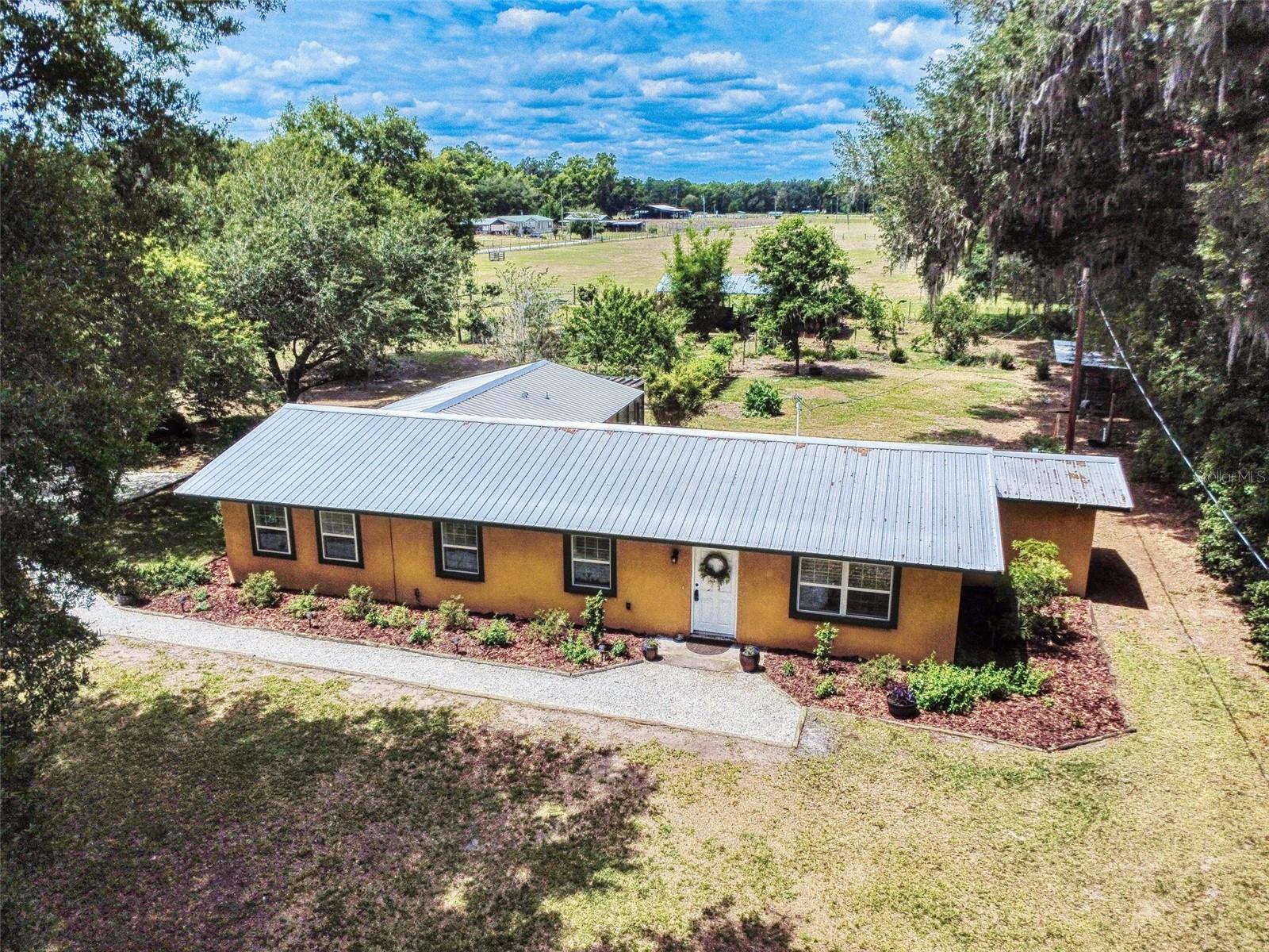 A True Country RETREAT!  ESCAPE BUSY CITY LIFE AND COME to the TRANQUILITY of RURAL LIVING with this BEAUTIFUL NEWER HOME THAT IS PERFECTLY set up for your AGRICULTURAL DREAMS.  This HOME WILL MEET YOU EXACTLY WHERE YOU ARE IN YOUR CHAPTER OF LIFE!!!!  FROM A YOUNG COUPLE PLANNING TO RAISE LITTLE ONES IN THE COUNTRY TO A RETIRED COUPLE ESCAPING THE HUSTLE AND BUSTLE!!  Located in the PEACEFUL COUNTRYSIDE OF WEBSTER, FLORIDA.  THE FULLY FENCED 10-ACRE AREAS ARE READY FOR HORSES, GOATS, CHICKENS, AND MORE!!  HOME WAS REBUILT IN 2020!!  A durable METAL ROOF offers peace of mind and LONG-TERM RELIABILITY.  As you approach the home, you are greeted by a private driveway and a GATED entrance, surrounded by gorgeous trees and an array of privacy landscaping.  This WORKING FARM features THREE CROSS-FENCED PADDOCKS, one with a POLE BARN equipped WITH TWO HORSE STALLS, and the remaining 2 PADDOCKS are used for ROTATING HORSES, LIVESTOCK, OR YOUR FAVORITE ANIMAL.  A second pole barn sits outside the paddocks, along with TWO CHICKEN COOPS, making this property well-suited for a variety of agricultural uses.  Enjoy exceptional PRIVACY WITH MATURE HEDGES, CLUSTER BAMBOO, and LUSH VEGETATION surrounding the property.  A FENCED GARDEN  with multiple RAISED BEDS and A VARIETY OF ESTABLISHED FRUIT TREES creates the perfect setting for sustainable living.  Relax on the screened-in rear porch with your morning coffee or tea, overlooking your animals and enjoying the peaceful surroundings.   The home offers a split floor plan layout with 3 bedrooms and 2.5 baths, plus a BRIGHT, OPEN-CONCEPT FLOOR PLAN.  Interior features include laminate flooring throughout, DOUBLE-PANE WINDOWS, and PLANTATION SHUTTERS for a clean, modern look.  The spacious primary suite includes a private en-suite bath with a tiled walk-in shower.  This property offers the opportunity to embrace the country lifestyle, grow your own food, enjoy your animals, and take in the beauty of your own private retreat.  Whether you're looking for a working farm, hobby homestead, or just a peaceful place to enjoy the countryside, this property offers the perfect blend of functionality, comfort, and charm.  PROPERTY LINES: refer to photo 57; the fenced area between the two roads and the row of trees are the property lines.  Over $50,000 spent on fencing alone!  Many vegetable and fruit-bearing trees.  Come make this your NEW HOME on your very own Farmstead.  Easy drive to Tampa, The Villages - where you have daily music with dancing, and entertainment every night - many outdoor dining options, shopping. Webster offers one of the largest flea markets on Mondays.