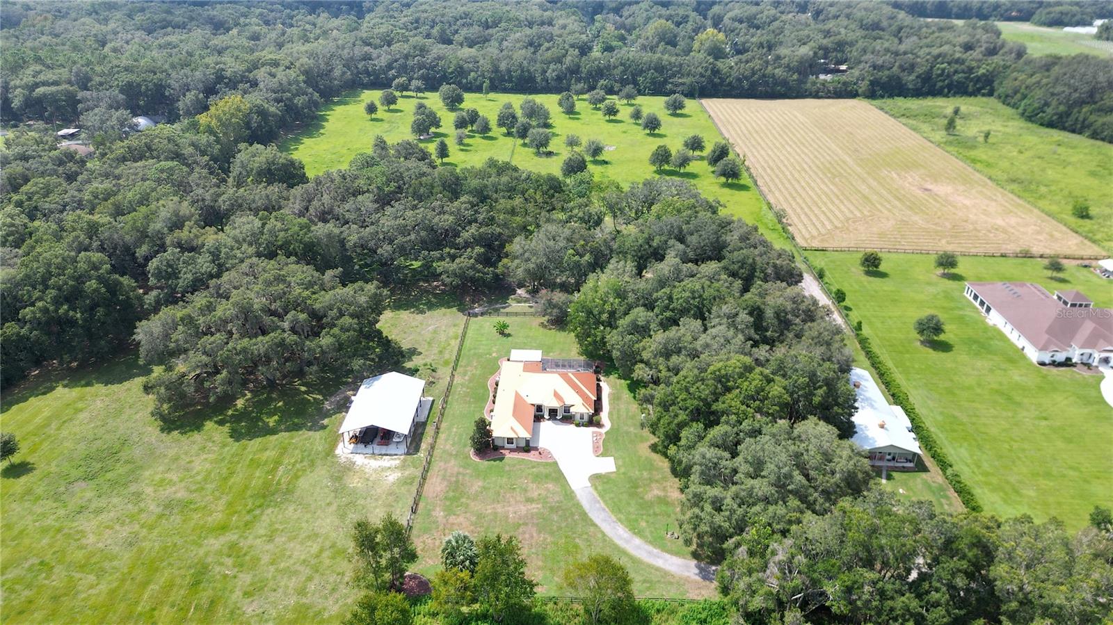 Discover this exceptional, turnkey, nearly 24-acre horse farm located in the Farmland Preservation district. Just 6 minutes from the World Equestrian Center (WEC) and 8 minutes to HITS, this property is a rare find. Upon arrival, you are greeted by beautiful aluminum privacy gates that open to reveal this exclusive estate. The turnkey stucco house features an open floor plan with 10 ft ceilings in the main living area, hardwood floors, high-end finishes, and a gourmet kitchen equipped with natural gas appliances. The family room is a highlight of the home, offering a contemporary linear fireplace and an illuminated tray ceiling that adds a layer of sophistication and ambiance. This space seamlessly transitions to the covered outdoor kitchen, which is a culinary enthusiast's dream. Complete with a deluxe grilling station, granite counters, a beverage fridge, and a prep sink, it's the perfect venue for entertaining and enjoying the property's scenic views. The primary bedroom is a sanctuary of comfort, boasting another linear fireplace, a tray ceiling for added elegance, and luxurious accommodations. The en suite primary bathroom features dual sinks, a luxury freestanding tub, a HUGE double walk-in shower, and a walk-in closet with laundry hook-ups, ensuring convenience and sophistication.  Relax in the screened-in lanai with a pool and hot tub, finished with brick pavers, surrounded by majestic live oak trees. 

HORSE FACILITIES

The estate is fully fenced and cross-fenced, providing a secure and picturesque setting for horses. The horse barn includes six stalls (with the potential for more), a climate-controlled tack room, a bathroom with washer and dryer, hot & cold water in the wash stall area, and a separate feed room. The property's equestrian facilities are further enhanced by a round pen and a 20 meter x 40 meter arena for comprehensive training and 40 X 60 barndominium.
An attached 2-bedroom, 2-bathroom apartment with high-end amenities offers additional income potential or comfortable guest accommodation. This high and dry estate combines the privacy of a secluded flag lot location with the convenience of proximity to essential amenities.
Ideal for those seeking unparalleled quality, privacy, and location, this horse farm and its expansion potential seamlessly blend luxury living with the best of equestrian lifestyle, enhanced by the ultimate outdoor living features.