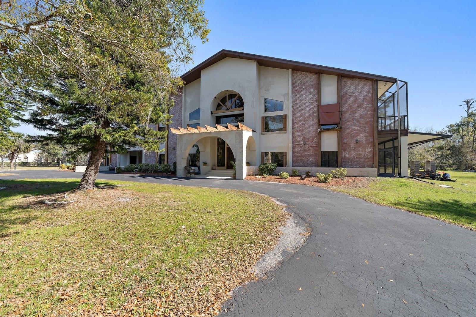 Unique Opportunity: This property offers the ability to be divided, providing the potential to build an additional home for family expansion, investment, or creating a multi-generational compound. Just had an appraisal and is priced below the appraised value! Exceptional opportunity to blend your passion for equestrian pursuits with the elegance of a luxury estate, set on nearly 11 acres in beautiful Odessa. Enter through a private gate and follow the winding drive to a stunning rural retreat, positioned to overlook a peaceful pond and surrounded by nature’s tranquility. This 6 bedroom, 8 bathroom estate embodies country living with modern luxury. The home features a bonus room that could easily be another bedroom, a side-entry 3½-car garage with workshop, circular driveway, and a porte-cochère that connects the residence and garage. Upon entering, you’re immediately welcomed by breathtaking 33-foot soaring ceilings, a cozy fireplace, elegant travertine flooring, and stone accent trim, all thoughtfully designed to frame spectacular pond views. One of the most sought-after features of the home is the downstairs in-law suite, offering exceptional flexibility. Located on the main level, the private suite has it's own bedroom, full bathroom, spacious walk-in closet, living room, and a private exterior entrance, ideal for extended family, guests, or multigenerational living. It can also easily serve as a primary suite on the main floor, providing true single-level living if desired. On the opposite wing of the home, the newly remodeled chef’s kitchen is nothing short of spectacular. Showcasing a striking blend of marble and granite countertops, custom cabinetry and lighting, a gas cooktop beneath a bronze-clad hood, and an oversized island perfect for gathering and entertaining. Adding a unique touch of timeless elegance, antique Egyptian doors mark the entrance to the kitchen, an unforgettable architectural statement. Behind another set of Egyptian doors, you’ll discover a hidden custom bar. Adjacent to the kitchen are a half bath and a generously sized laundry room accented with bronze countertops. Ascend the staircase to the second level, where expansive wall space provides the perfect gallery for artwork. Here you’ll find four additional bedrooms plus an office, with each bedroom offering its own private bathroom, high ceilings, and incredible pond views. A wraparound balcony spans this level, allowing you to fully appreciate the surrounding wooded landscape and water views. The primary suite is truly a retreat of its own, featuring vaulted ceilings, a large walk-in closet, and a spa-inspired bathroom complete with triple sinks, a dedicated makeup area, and an oversized shower. Step outside to the expansive screened balcony, which wraps around the back and one side of the home, an ideal setting for relaxing, entertaining, or simply enjoying the serene pond views. The outdoor amenities are equally impressive. A charming 2 story small animal barn with a metal roof — fondly known as “Happy Hare”, offers endless possibilities as a retreat, man cave, she shed, or hobby space. Golf enthusiasts will appreciate the private putting green, while equestrians will love the close proximity to a nearby nature preserve with nearly five miles of scenic riding trails. This exceptional estate delivers a truly rare lifestyle—where luxurious living, privacy, and outdoor adventure come together to create the ultimate private sanctuary.