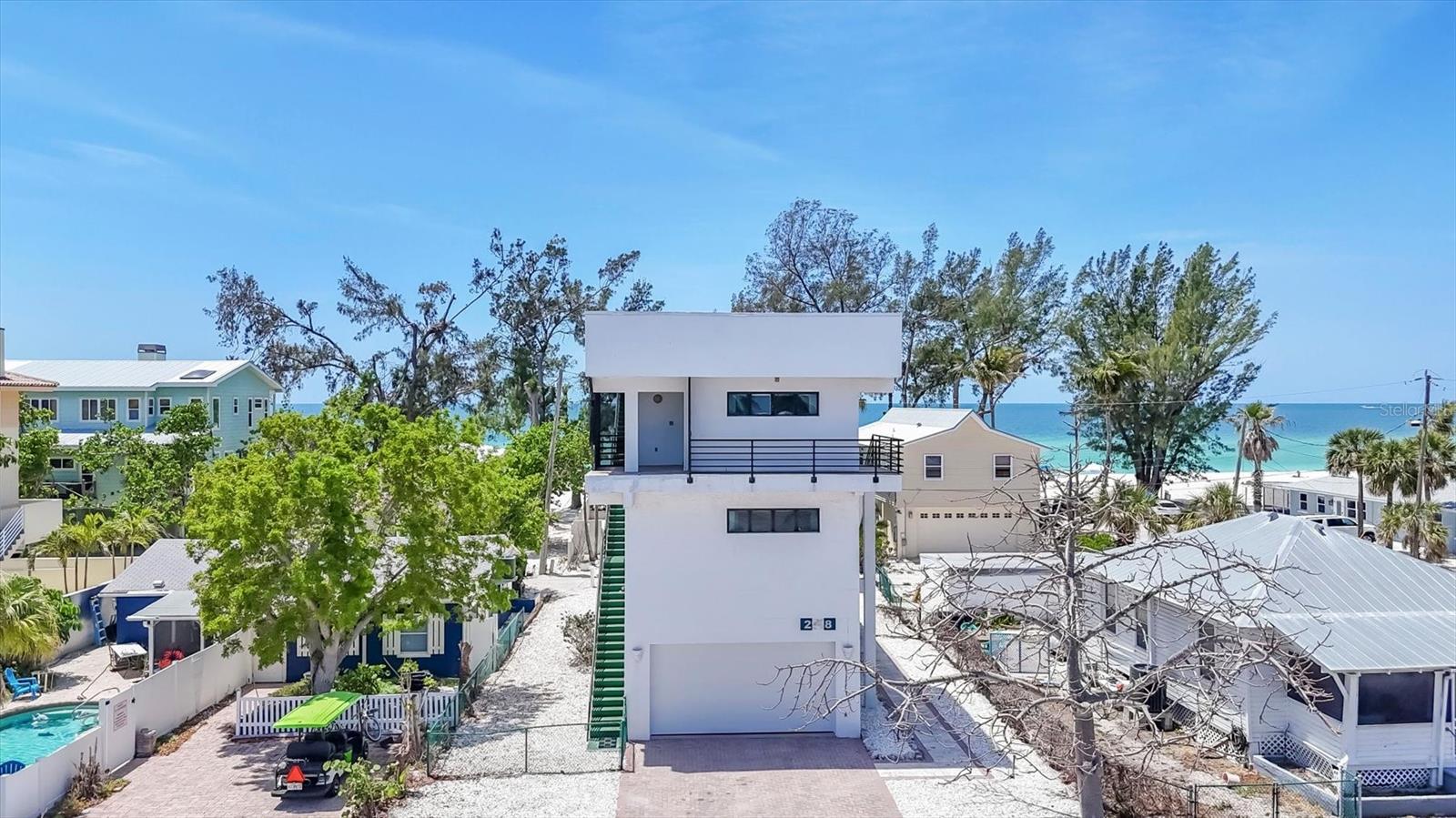 One or more photo(s) has been virtually staged. This incredible home is built like a fortress. This architect designed concrete tri-level residence was constructed with artistry and represents a masterpiece of strength framed by a concrete girdle wrapped around solid pilings. Wake up to the scent of salt in the air and the sound of waves just steps away, this is not a vacation, this is your everyday! Picture yourself walking barefoot at the beach just about 500 feet from your home, everyday!  The European 2 person elevator glides you through 2262 square feet encompassing 3 bedrooms, 2 bathrooms, an open kitchen, dining room and multiple living areas to the rooftop retreat where Gulf views await stretching endlessly Westward. The details of this home are custom for this one of a kind beach residence. Features include richly hued cherry wood floors, a 2025 primary bathroom shower conversion, electric roll-down hurricane shutters for peace of mind, a 2024 newer roof, a 2025 hurricane rated garage door and poured in place concrete exterior stairs located on the North and South.. Utilities are located underground. Enjoy Caribbean quality sunsets night after night over the gulf for jaw dropping vistas. Step onto one of the breezy balconies with your morning coffee for an incredible way to begin your day! At day's end, climb on up again to your private rooftop perch, kick back and inhale the sea air. Whether you're lounging in the living areas, gathering with friends in the family room, taking in panoramic views of the Gulf or taking the elevator down for a barefoot walk on the shoreline to collect shells and watch the sunset you'll be living your life like a vacation - every day! Be sure to check out the 3D Virtual Tour. One or more photo(s) has been virtually staged.