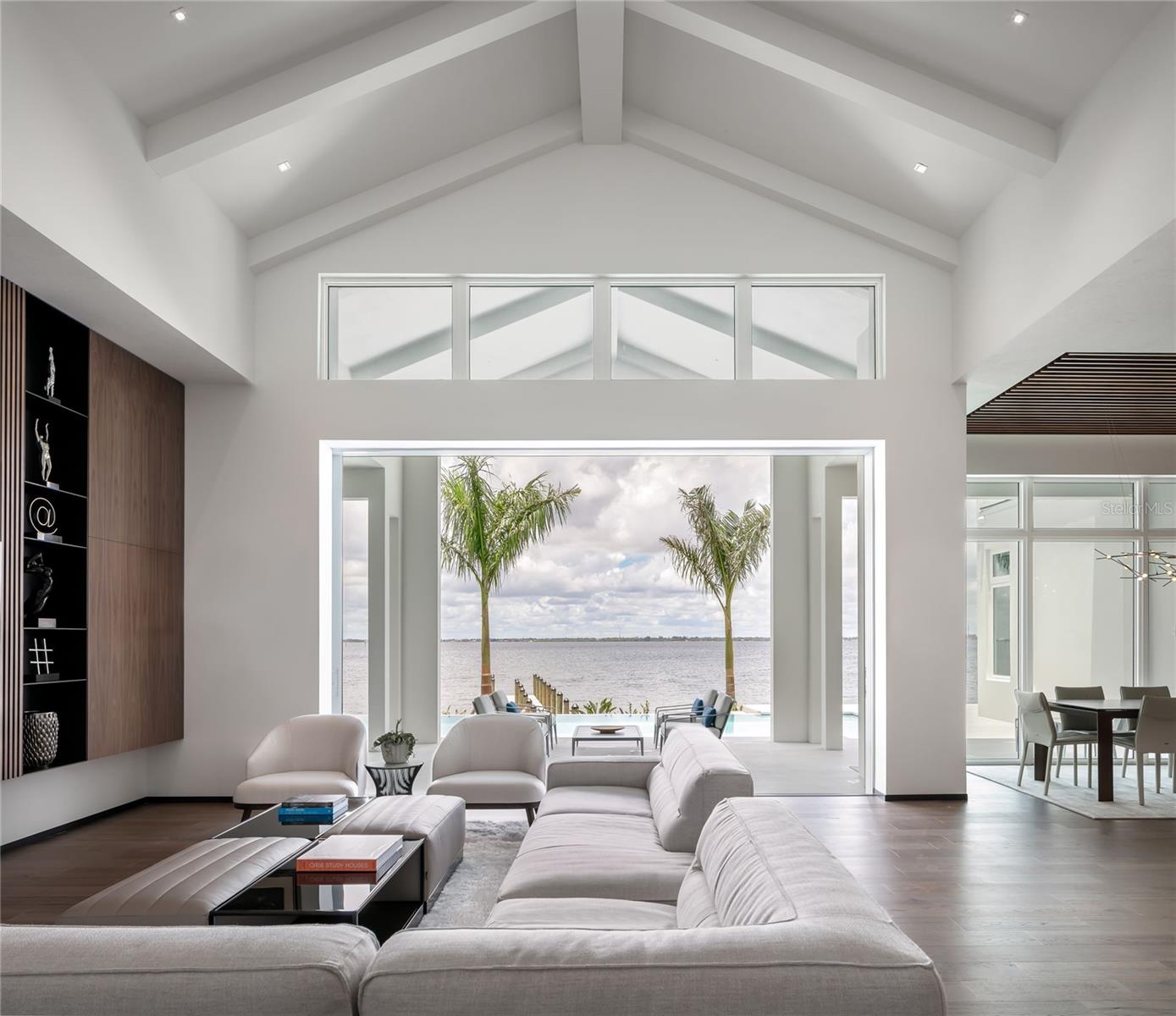 A rare opportunity to own a custom architecturally designed award-winning harbor front home. This home was recently featured in the March 2023 issue of Gulfshore Life, southwest Florida’s luxury lifestyle magazine and was featured in Sarasota SRQ Magazine Home of the Year 2021 and awarded the Platinum Award for best overall Interior Design. Over 4700 gross SF on one level, panoramic wide water views from sunrise to sunset. Interior Design by Hive Architects, this offering separates itself from all others with an unrivaled combination of quality, ultra-luxe materials, with Control 4 technology. 86 feet of direct harbor frontage is framed with banks of sliders and floor-to-ceiling windows for abundant lighting throughout. The dramatic foyer leads to an expansive living area, towering, detailed ceilings where the open floor plan flows from a custom-built wine bar to the Epicurean kitchen with walnut cabinetry, top-of-the-line Dacor Modernist series appliances, double convection ovens and induction cooktop. Owners will retreat to the main level primary suite with generous boutique closet systems (14'x15' walk in closet). Soak in a spacious spa bath or shower in the large walk-in shower with multiple adjustable heads. Flowing stained wood floors, walnut cabinets, light quartz countertops, and monochromic wall tiles, the material palette is simple, calm and modern. Juxtaposing but complementing the rich palette of natural textures are hot rolled steel accents in the wall base and custom shelving units bring a subtle industrial touch to this refined earthly palette. Custom wood paneling and built-in-wall systems are designed to look fully integrated in the great room, kitchen, primary suite, and den/4th en-suite bedroom. Echoing the textural quality of the custom casework, wood elements with integrated light fixtures were implemented into the ceiling of the entry space, dining room and primary bathroom. The modern aesthetic transcends in the selection of the brushed stainless steel plumbing fixtures and minimal light fixtures. The lanai is the highlight where the outdoor area offers multiple entertaining spaces with a summer kitchen and an impressive 41-foot vanishing edge saltwater pool, spa and 80-foot dock. Coveted three car storage, full house generator, audio and surveillance security included. Join the Isles Yacht Club and enjoy “the Punta Gorda Life in Motion….” Nautical Connection without Congestion”. Located in Punta Gorda, a cozy close-knit town with royal palmed lined streets, perennial gulf winds and a quaint seaside downtown that draws sailors, anglers and boaters alike. Adventure is personified here, patriotism is flowing, a bounty of organic locally grown produce, tournament fishing, regattas, and festivals galore. Cyclists and pet friendly parks link the 17-mile path and promenade around the city. Foodie deliciousness flourishes at farm-to-table restaurants. Punta Gorda airport offers nonstop flights to 50+ destinations. Charlotte Harbor is a 270 square mile prized estuary where the Peace River and the Myakka rivers connect to the Gulf Islands and beyond. This is 2020 Jamaica’s Way’s magnetic appeal. Imagine living in the natural beauty and wildlife surrounded by modern architecture.