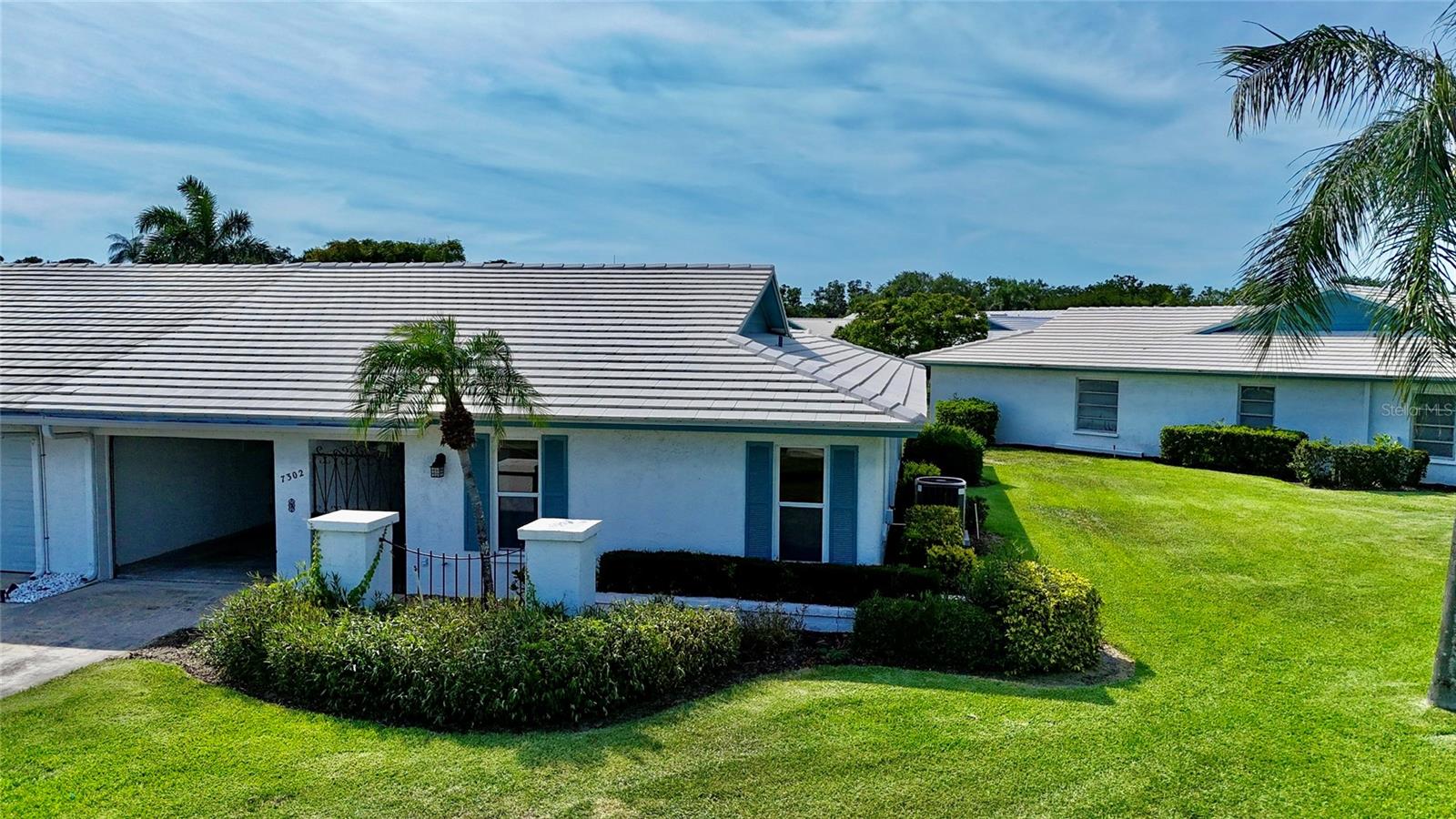 Village Green 55+ community located walking distance from Publix and some of NW Bradentons favorite restaurants. Enjoy the Florida lifestyle in this 2 bedroom 2 full bath 1745 sq. feet of open concept living. Take a stroll in the park or take in a quick dip in the swimming pool to cool off in the warmth of the sun. This floor plan has been tastefully updated in the kitchen and baths with Solid surface counters, Kraft Made solid wood cabinets and an expanded coffee bar and additional cabinet storage. You can enjoy the Florida sunrises and sunsets from both sides of the villa or relax in the air conditioned Florida Room. The flooring has been updated offer a hand hune engineered floor giving the home a warm and comfortable feel. The unit has a one car garage and plenty of storage in the garage rafter area above. Located at the gateway to Anna Maria Island at 75th and Manatee Ave, this location is ideal and in a Non Flood Zone area. Come and explore spacious living at prices that will take you back to the good old days.