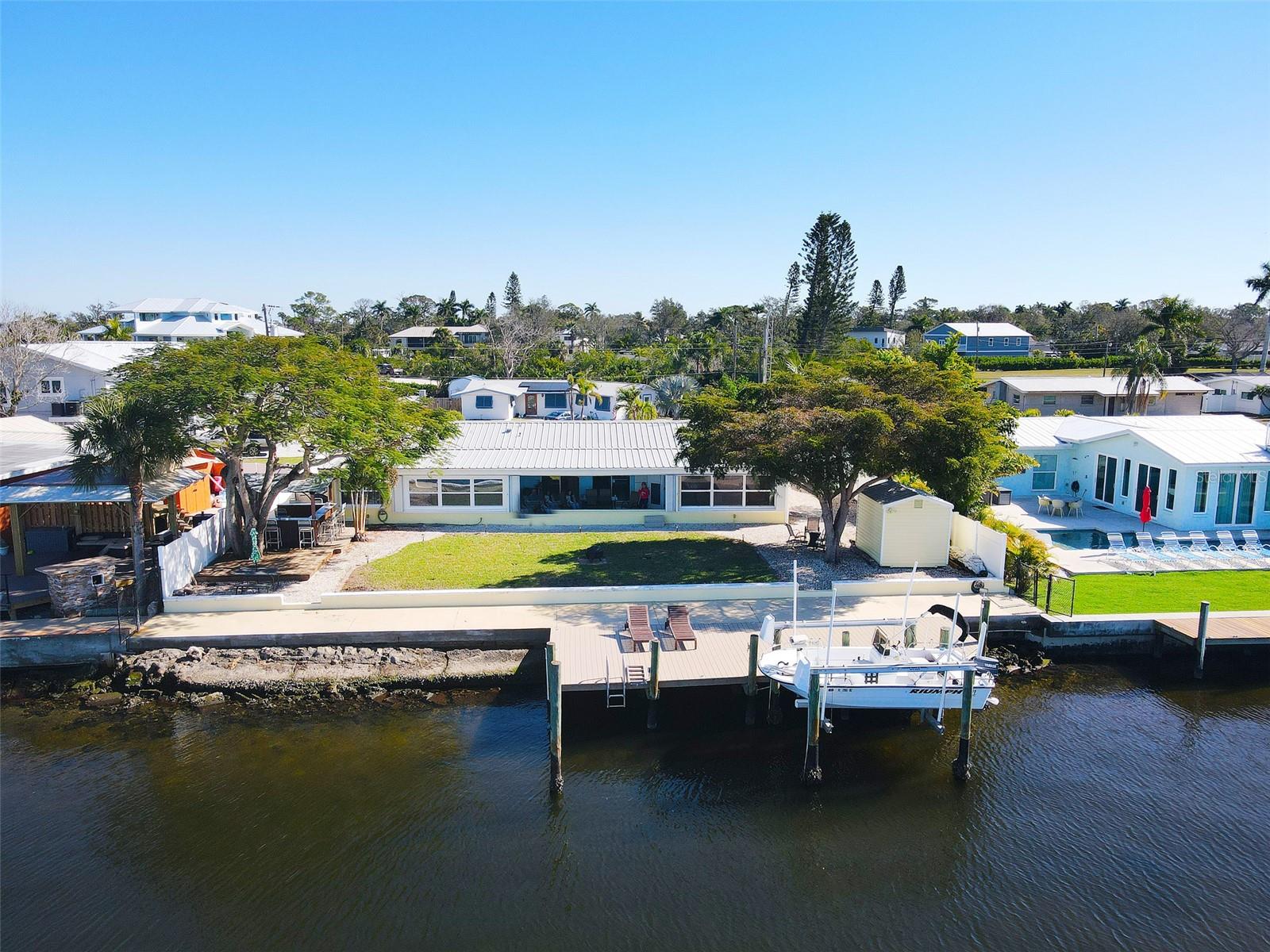 NO HOA and direct Gulf access! Welcome to this turnkey furnished, urban, waterfront, four-bedroom, three bath classic Florida block construction home tucked away on a quiet cul-de-sac offering 90 feet of Manatee River frontage! A one-of-a-kind, absolute must-see gem with breathtaking sunsets, pet friendly, fenced yard. Avid boaters will appreciate the water location, new seawall, private composite dock, Tiki Bar, and boat lift. There's also a detached shed and RV parking with 30-amp hookup.

This roomy, rambling, waterfront ranch layout offers a perfect floorplan for a lucrative fisherman's Airbnb, guests, or multi-generational living. Three bedrooms provide private entrances. The private 4th bedroom includes an ensuite bath and its own entrance, ideal for guests seeking privacy. The Sunroom, Office and open air/undercover patio full views of the Manatee River and downtown skyline equipped with a 2nd fridge, A dual-entry covered breezeway with wrought iron screen doors welcomes you inside to a comfortable living/kitchen combo with granite countertops, a pot-filler at the stove, and a spacious breakfast bar. A hidden pocket door can separate the two bedrooms, bath and office on the south side of the home, providing additional privacy if needed.

The home offers unique, vintage, mid-century touches such as the built-in bookcases, cupboards, cedar closet, tongue & groove pine ceilings in bathroom, a wet bar just off the kitchen, along with a large laundry room, interior workshop/storage area equipped with a deep freezer, and a pre-plumbed steam-shower space. Several split units control energy-efficient, individualized and customized temperature and comfort throughout the home. Plus, a full-size outdoor antenna can stream those local TV channels in the event of an internet/cable outage. 

Centrally located within 3 miles to Downtown Main Street, Manatee Memorial, Twin Dolphin Marina, Pier 22, Manatee Players Theater, Central Library, and Bradenton Riverwalk. This is an exceptional opportunity that cannot be duplicated, with flexible living spaces, one-of-a-kind sunset views, waterfront amenities, this home offers a rare blend of comfort and versatile Florida waterfront living.