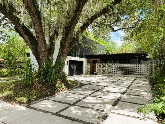Welcome to 2506 Woodside Ave — a meticulously appointed 2017-built home with distinctive modern architecture tucked into one of Orlando's most beloved and established neighborhoods. Clean lines, bold design, and an unmistakable contemporary presence set this home apart on a street of charming older Florida homes and newer construction alike. Surrounded by mature trees and quiet streets where neighbors know each other, this property combines mid-century modern design with a welcoming neighborhood atmosphere.

The main residence includes 3 bedrooms and 2.5 bathrooms, with the total property — including a private guest studio — encompassing approximately 2,642 square feet on a 69 x 125 ft lot. The home's interior is finished with the same intention as its exterior: slate floors flow throughout the first level, rich hardwood carries through the upstairs, and the bathrooms feature slate tile, with one showcasing elegant marble floors. Granite countertops and Moen fixtures in the bathrooms and throughout the door hardware complete an interior where every detail was chosen deliberately. KitchenAid appliances anchor a well-appointed kitchen. Every room is equipped with dimmer-controlled lighting, and the home was constructed with non-cellulose sheetrock — a moisture-resistant choice well suited to the Florida climate.

All bedrooms include ceiling fans, as does the living room. A dedicated laundry room with side-by-side washer and dryer, built-in storage, and clothes drying area adds convenience and functionality. The attached two-car garage, whole-home Generac generator system, Culligan whole-home water softening system, and Raintree irrigation system covering both the front and back yards provide infrastructure designed for Florida living.

Step outside and the property truly shines. A resort-style salt-generating pool anchors the backyard, flanked by distinct outdoor entertaining spaces: two decks, one with a built-in bar and a separate covered porch with an outdoor TV and ceiling fan, creating an inviting outdoor living spaces that can be enjoyed throughout the year.

The detached back studio includes a murphy bed, full bathroom, and separate kitchenette area with a breakfast bar, sink, microwave, and space for a small refrigerator. The flexible layout supports a variety of uses, including a home office, studio, workspace, guest accommodations, or additional recreational space. Rarely found in homes of this caliber, the detached studio adds functionality and versatility to the property.

With no HOA and located on a uniquely quiet street with no through traffic, the setting is both peaceful and convenient. Two parallel roads connect at the lake, creating a distinctive pocket of the city. Audubon K-8 just blocks away, while the restaurants and shops along Corrine Drive, as well as Winter Park, Baldwin Park, and downtown Orlando, are all easily accessible.

A distinctive modern home in one of Orlando's most sought-after neighborhoods, 2506 Woodside Ave presents a unique combination of thoughtful design, quality construction, and exceptional outdoor living.
