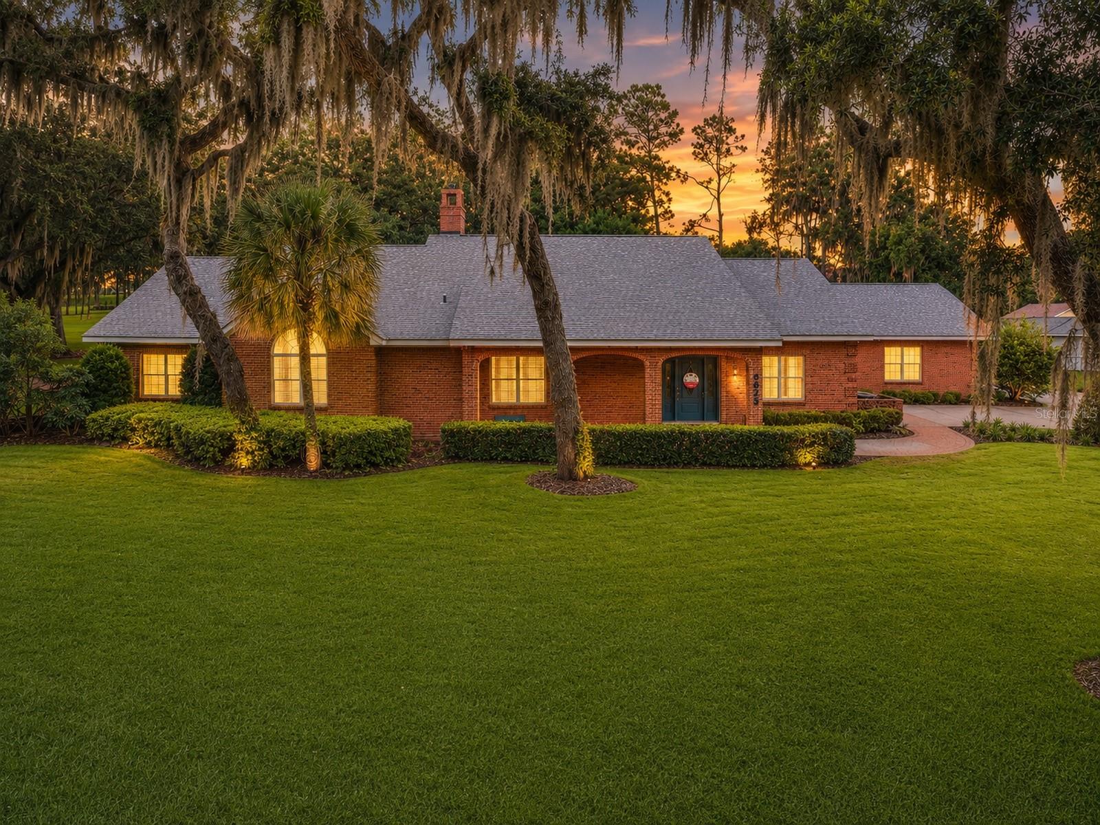 Virtually Staged. ONE-OF-A-KIND CUSTOM BRICK ESTATE | PRICED BELOW APPRAISAL VALUE| NO HOA | JUST UNDER 2 ACRES | OVER 4,400 SQ FT | WHOLE HOUSE GENERATOR | WORKSHOP | STORAGE GALORE! Welcome to a truly exceptional property where timeless craftsmanship, Southern charm, & the tranquility of Old Florida come together. Nestled beneath majestic oak trees draped in Spanish moss on just under 2 acres with NO HOA, this custom-built estate offers 4 bedrooms, 2.5 baths, & a lifestyle that is nearly impossible to replicate. With the warmth & character of a mountain lodge combined w/ the beauty of Fl living. From the moment you arrive, you'll appreciate the expansive grounds, inviting covered front porch, & classic brick architecture that create an unforgettable first impression. Inside, exceptional craftsmanship is evident throughout with soaring ceilings, exposed wood beams, custom built-ins, and storage at every turn. Elegant formal dining is designed for memorable gatherings & holiday celebrations, featuring tray ceiling & built-in china cabinet. The heart of the home is the impressive chef's kitchen, offering solid wood cabinetry, granite countertops, pull-out shelving, & a spacious center island. Just around the corner, you'll discover one of the home's most impressive features—a massive 6' x 12' walk-in pantry, providing exceptional storage and organization rarely found in today's homes. The living room is warm, inviting, & filled with character, showcasing soaring ceilings with wood beams, a built-in wood entertainment center, & a cozy gas floor to ceiling stone fireplace. French doors lead into the incredible Florida room, where walls of windows flood the space with natural light and provide peaceful views of the surrounding property, creating the perfect place to relax year-round. Spacious primary suite was thoughtfully designed as a private retreat and offers storage in every corner, including a built-in armoire, two walk-in closets, & a beautifully designed custom walk-in tile shower. Built-in cabinetry continues down the hallway leading directly into the utility room, creating seamless organization throughout. The utility room itself features additional built-in cabinetry and workspace, making everyday living effortless. Need a home office or additional bedroom? The versatile office/den features a custom built-in desk, a walk-in closet, and could easily be converted into a 4th bedroom to fit your needs. If storage is on your wish list, this home delivers beyond expectations. Just off the attached 2-car garage is an incredible 23' x 8' storage room, perfect for seasonal décor or organizing all of life's extras. For the woodworking enthusiast, classic car collector, or anyone dreaming of the ultimate hobby space, you'll absolutely fall in love with the 27' x 20' under-air workshop. Attached directly off the garage, this incredible space even features its own half bath. Outside, the possibilities continue with 2 detached sheds equipped with electricity, providing even more storage for equipment, lawn tools & more. And when hurricane season arrives, you'll enjoy peace of mind thanks to the whole-house generator, ensuring your home remains comfortable and functional during storms & power outages. Every detail of this property reflects quality craftsmanship & timeless design. Combining nearly 2 acres, custom architecture, incredible storage, a dedicated workshop, and the freedom of NO HOA. Exceptional features and endless charm make this a must-see property!