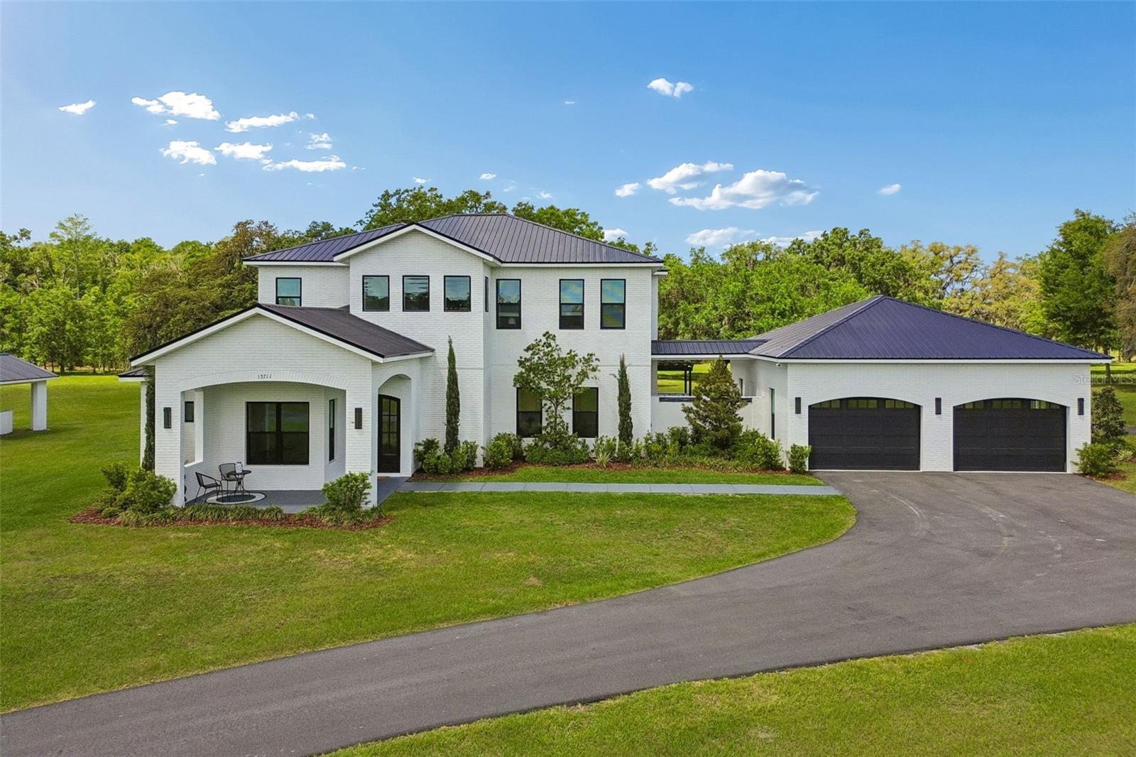 Welcome to your private luxury retreat set on almost 25 lush, picturesque acres in Pasco County where timeless elegance meets serene natural beauty. This "French Country Estate" is surrounded by vibrant greenery and overlooking tranquil pond views, this exceptional 5-bedroom, 5.5-bath estate offers over 4,500 square feet of refined living designed for both comfort and grandeur.

From the moment you enter, a grand Harlequin marble-floored foyer introduces the home’s sophisticated design and leads into an expansive open-concept living space. Soaring ceilings with exposed wood beams create an airy, dramatic atmosphere, while an elegant electric fireplace and walls of sliding glass doors seamlessly connect indoor and outdoor living.

The gourmet kitchen is a true centerpiece, featuring a coveted La Cornue French gas range and premium Thermador appliances (two refrigerators and two freezers!). Tucked just off to the side, an expansive butler’s pantry offers exceptional functionality—ideal for seamless entertaining, additional prep space, and keeping the main kitchen effortlessly clean and enjoyable.

Each bedroom is thoughtfully designed as a private suite, complete with its own ensuite bath and walk-in closet. The primary suite offers a peaceful escape with a spa-inspired bathroom and a private balcony overlooking the surrounding landscape. Multiple balconies throughout the home provide stunning vantage points to enjoy the property’s natural beauty.

For automotive enthusiasts, the climate-controlled 4-car garage is a true car collector’s dream, offering both function and showcase appeal. A striking breezeway with a tranquil waterfall feature adds to the home’s resort-like ambiance.

Perfectly positioned just minutes from Tampa, this estate delivers unmatched privacy without sacrificing convenience. Just around the corner, the newly opened Moffitt Cancer Center at Speros Outpatient Center—which began treating patients in January 2026—adds to the area’s growing appeal. Altogether, this is a rare opportunity to enjoy luxury living immersed in nature while remaining close to modern amenities.