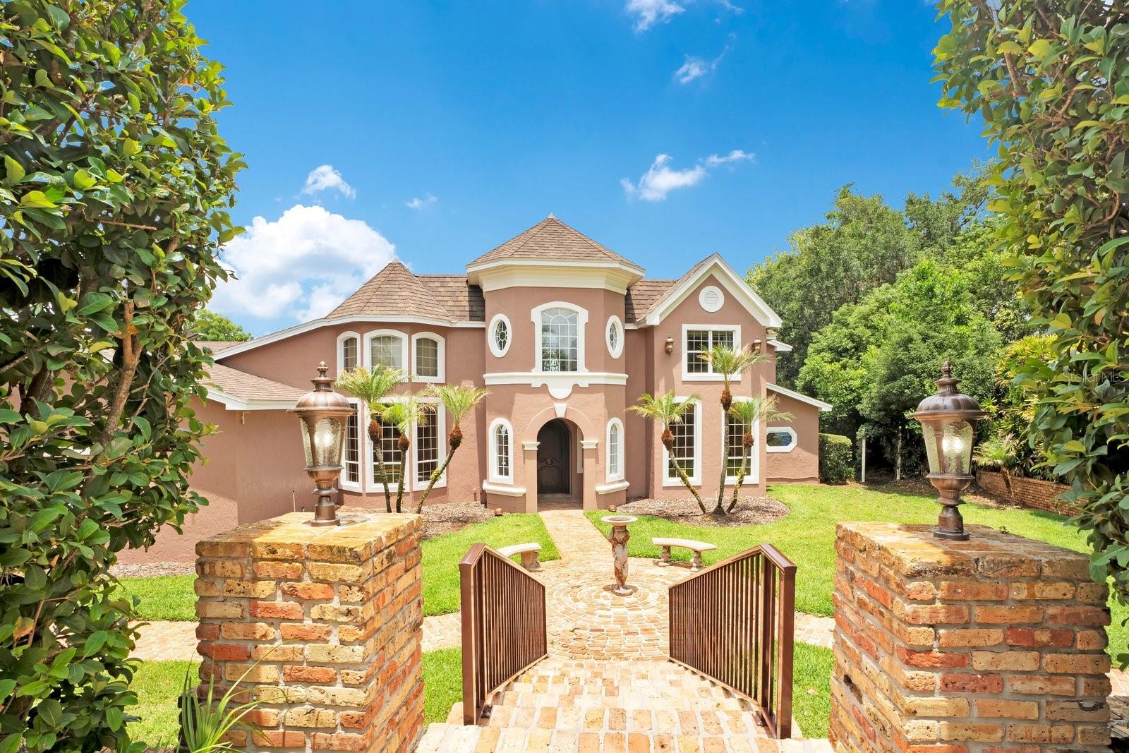 Nestled within a private gated community on 1.6 sprawling acres along the shores of Lake Arietta (a pristine 739-acre private lake), this south-facing Mediterranean Revival estate offers an unparalleled sanctuary of luxury. A grand circular drive leads to a dramatic entryway featuring a hand handcrafted front door by Gregor(previously featured in Architectural Digest). The interior boasts soaring ceilings, opulent travertine and rich wood flooring, crystal chandeliers, wrought iron balustrades, and a Chicago brick fireplace with an imported Trumeau mantel.

Designed for the epicurean, the main kitchen features premium cabinetry, granite countertops, a Sub-Zero refrigerator/freezer, and a professional-style dual-fuel gas range, plus a morning kitchen with dual wine cabinets. The expansive family room features slate floors and corner stacking sliders framing panoramic pool and lake views. Perfect for entertaining, the indoor climate-controlled second kitchen boasts a commercial Captiveaire hood with industrial ventilation/fire suppression, specialized Fire Magic professional-grade grills, a 1200-degree searing station, Recteq wood pellet grill, Aurora gas grill, keg cooler, and ice maker.

Luxury amenities abound: a custom 300-bottle wine cellar, a state-of-the-art movie room wired for whole-home audio (equipment conveys), and a Florida room under a vaulted tongue-and-groove wood ceiling with a wet bar and bay windows. The palatial downstairs primary suite serves as a private oasis with a sitting area, private lanai, lake views, custom walk-in closet with an independent washer/dryer, and a lavish bath with a copper sink and Brizo rain-head shower system. Upstairs features a split plan with 4 bedrooms and 2 baths (one ensuite; three sharing a Jack-and-Jill bath).

The outdoor oasis features a saltwater pool with Pentair controls, a vanishing-edge waterfall, a hot tub, and a sunset grotto with waterfall. A pristine boat dock (built 2025) features a 2-craft capacity, fully equipped with an electric boat lift and a dedicated personal watercraft (PWC) lift. The entire estate is backed by a full-home Generac generator. Parking includes an oversized attached 3-car garage plus an immense, detached 2,500+ sq ft RV garage. The RV space is fully air-conditioned (5-ton system) with two 18x16 doors, doubling as a luxury pool house with a full bath. An adjacent oversized parking area includes two additional RV hookups and flush-outs. A masterful convergence of architectural elegance and recreational indulgence on a premier private lake!