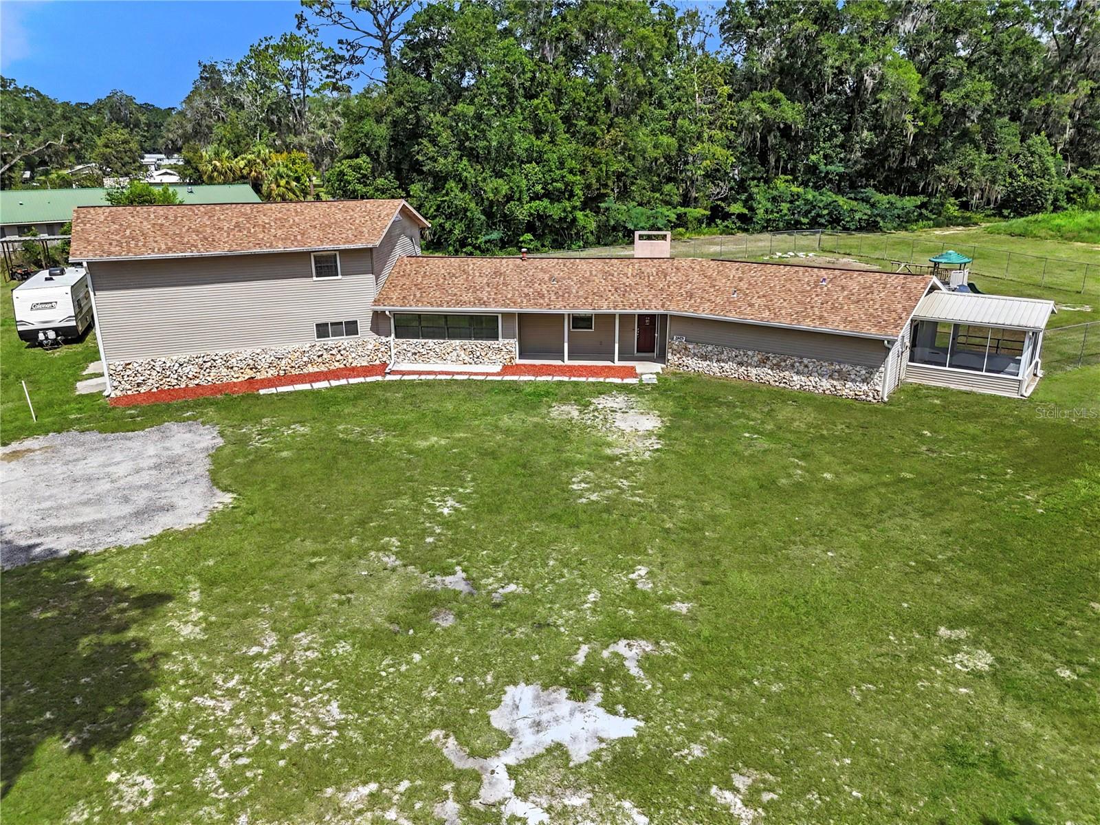 Virtually Staged. Welcome home to your beautiful and unique property nestled right outside the city limits on almost 5 acres! This home has so much to offer. You certainly need to see it to appreciate it. The deeded easement leads you back off the main road into the property. It is peaceful and PRIVATE with beautiful trees and plenty of room to run, play, plant a garden, enjoy your animals all while being totally secure, the entire perimeter is fenced. Imagine the fun gatherings you can have here!   There is a 2nd well on the back of the property and plenty of room for a second home. When you enter the home there is a nice large entryway that looks into the family room with tons of natural light and a gorgeous stone fireplace. Such a great room to get cozy in. The main part of the home offers 2 large guest bedrooms as well as a master suite with its own screened in porch and a large walk in closet. The master bathroom is roomy with an oversized shower that is sure to please!! The kitchen offers wood cabinetry and the view from the kitchen window is one you are sure to love for years to come. Through the dining room you have a nice large breezeway that could be easily converted into a pretty amazing mudroom. The large Living room has a beautiful set of french doors so that the space can be closed off for privacy if needed. There is also additional storage! The bar area, Billiards/game room does not disappoint. A great space for entertaining with beautiful wainscoting around the room. There are so many possibilities for this space!! The stairs will lead you up to two very large bedrooms that would be a great space for guests when they visit, for older children that need their own space, to use as an in-law suite or for additional short term or long term rental income!! If you are really creative it could also be an amazing space for a home theatre.  This space has been finished out with vinyl plank flooring and a third full bathroom. There is plenty of storage space inside! A 30x40 metal shop is sure to be a dream for enthusiasts or a spot to use for a small business shop and there is lots of extra room for additional storage!! There is full electric including 2 RV electric hook ups. Dont forget the POOL, new vinyl liner in late 2021! Dont miss the opportunity to own this unique gem of a property that is also very conveniently located. 10 mins to downtown Ocala, shopping and dining just a short drive in any direction, less than 15 minutes to I75 and about 15 mins from the World Equestrian Center!!  ROOF 2022.  WATER HEATER 2022.